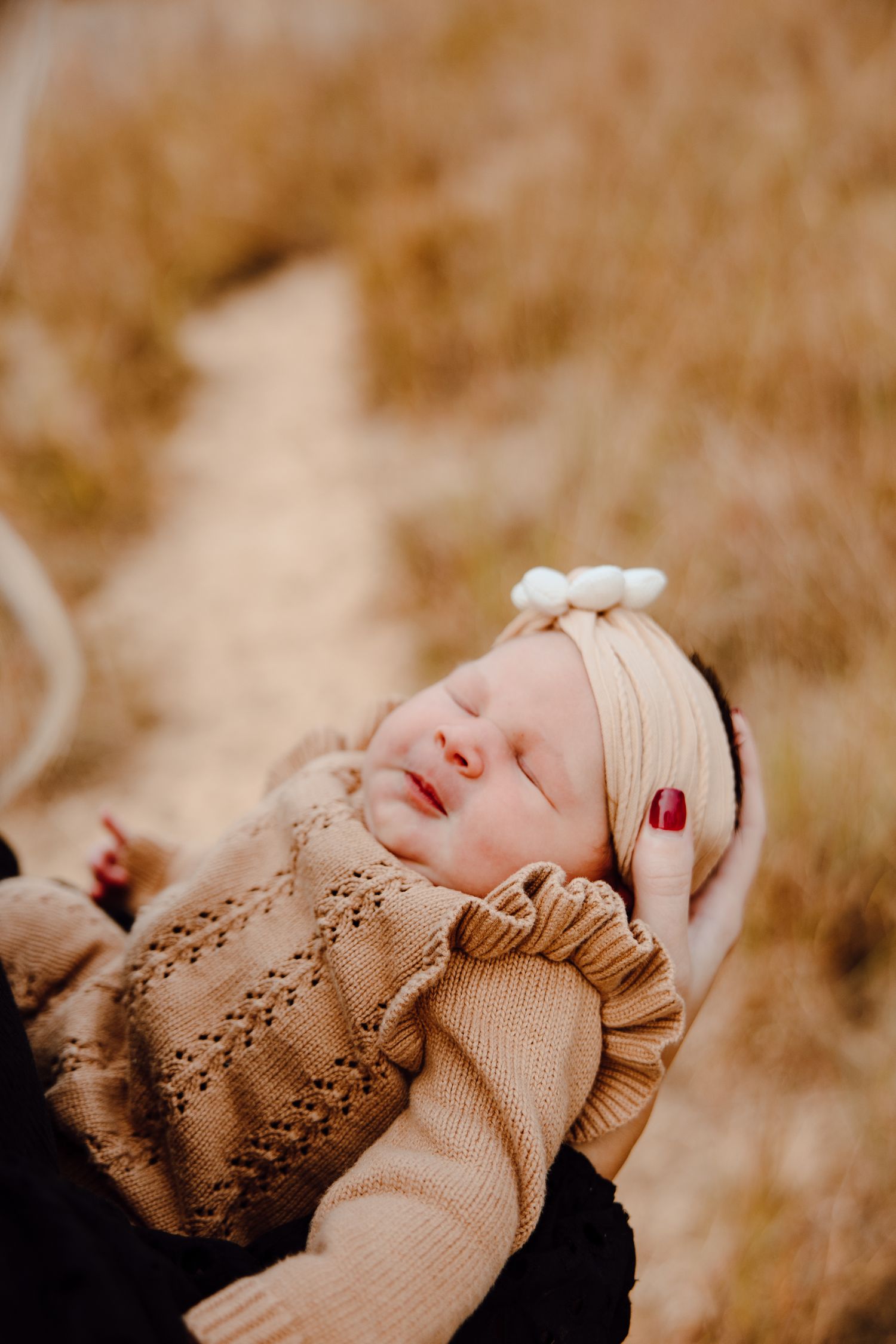 Sleeping infant wearing knit sweater in warm autumn tones.