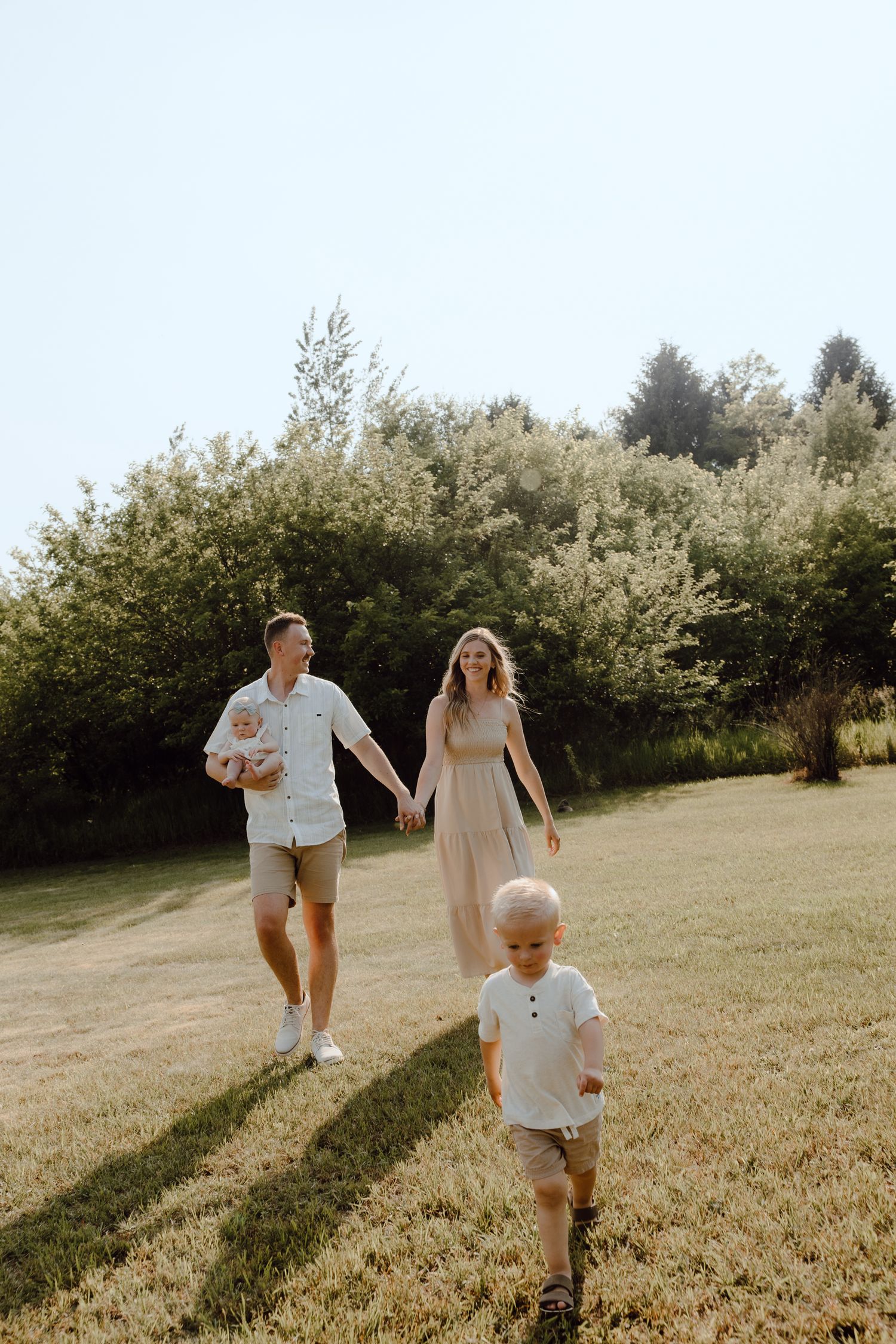 Family enjoying a playful moment while walking through a sunlit meadow.