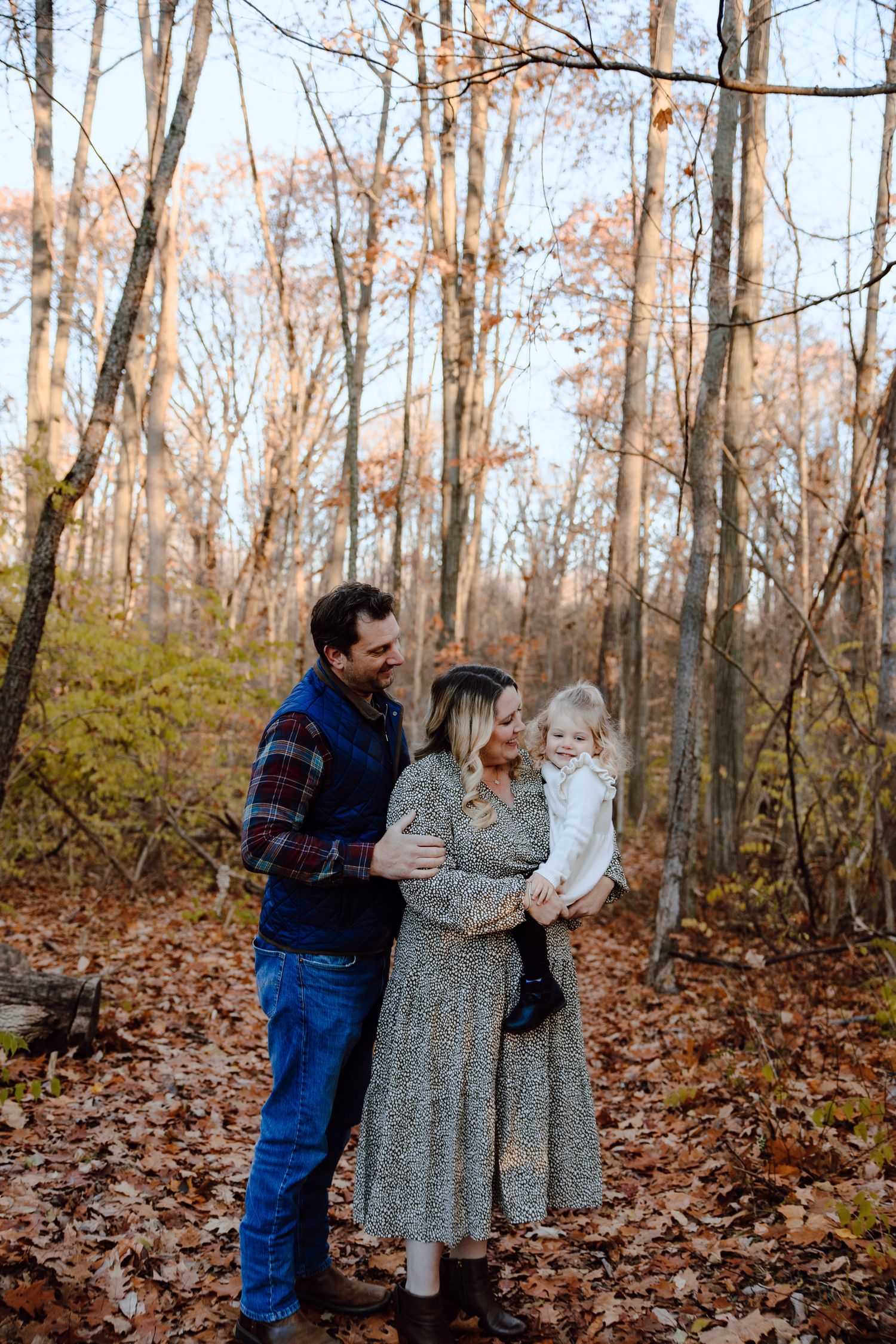A family shares a loving moment together in an autumn forest setting.
