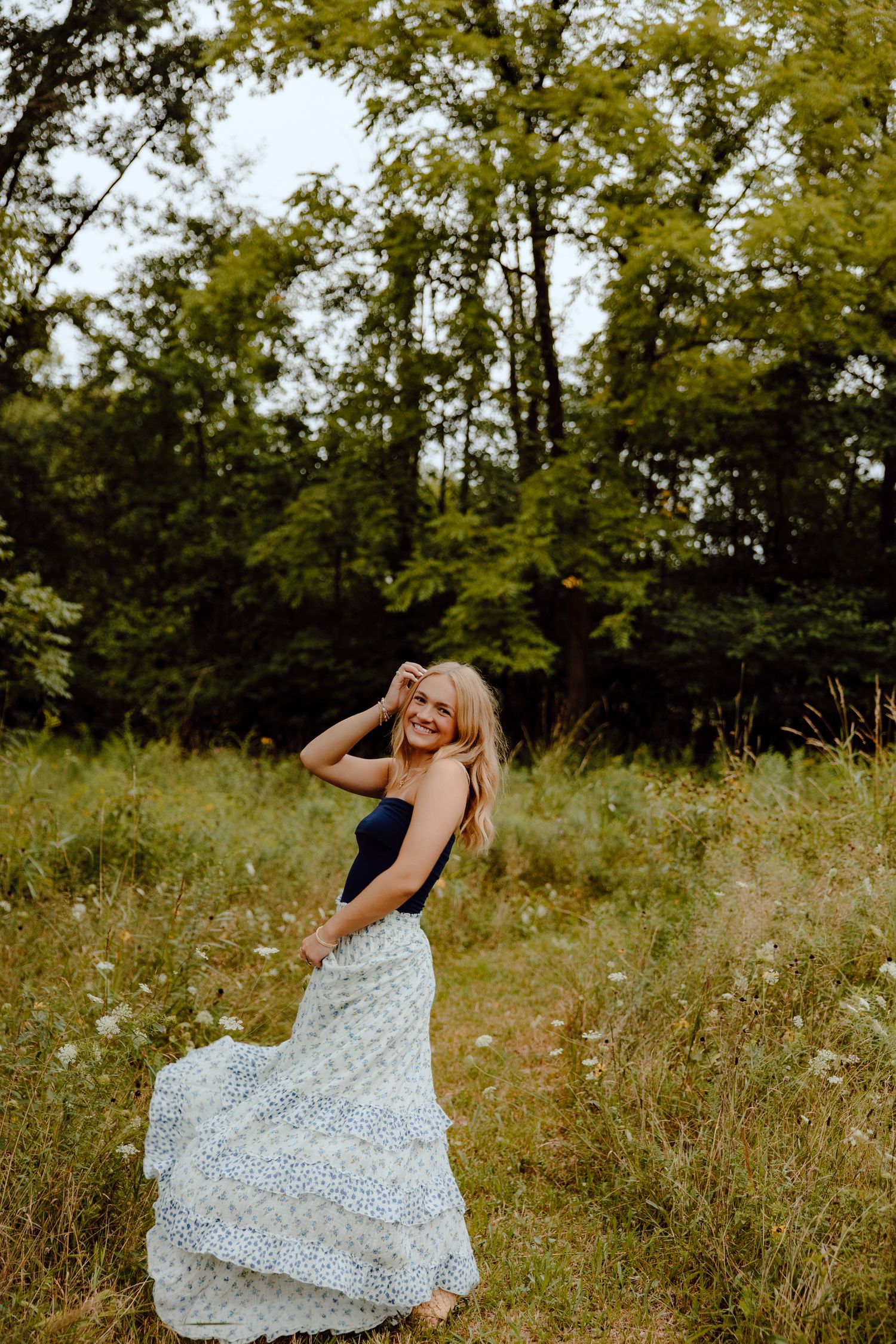 Dancing figure in a floral dress spins through a summer meadow at golden hour.
