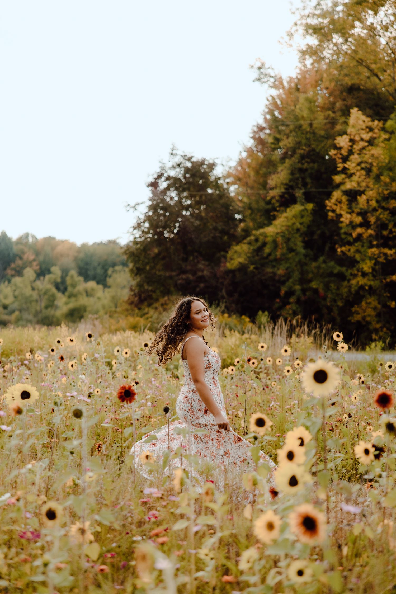 A floral sundress stands out against a dreamy field of sunflowers and wildflowers on a warm autumn day.