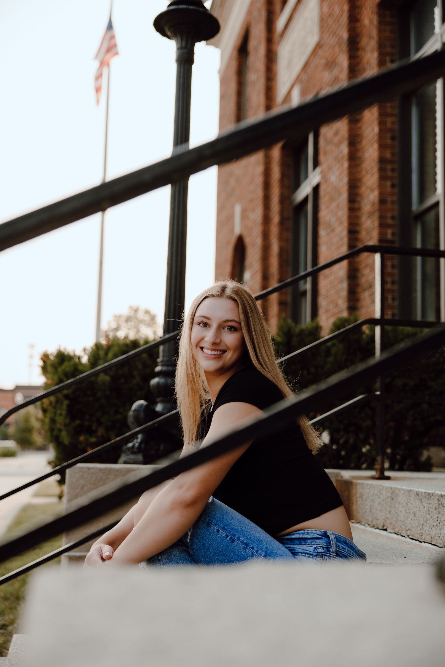 Person lounging on concrete steps near brick building with casual pose.