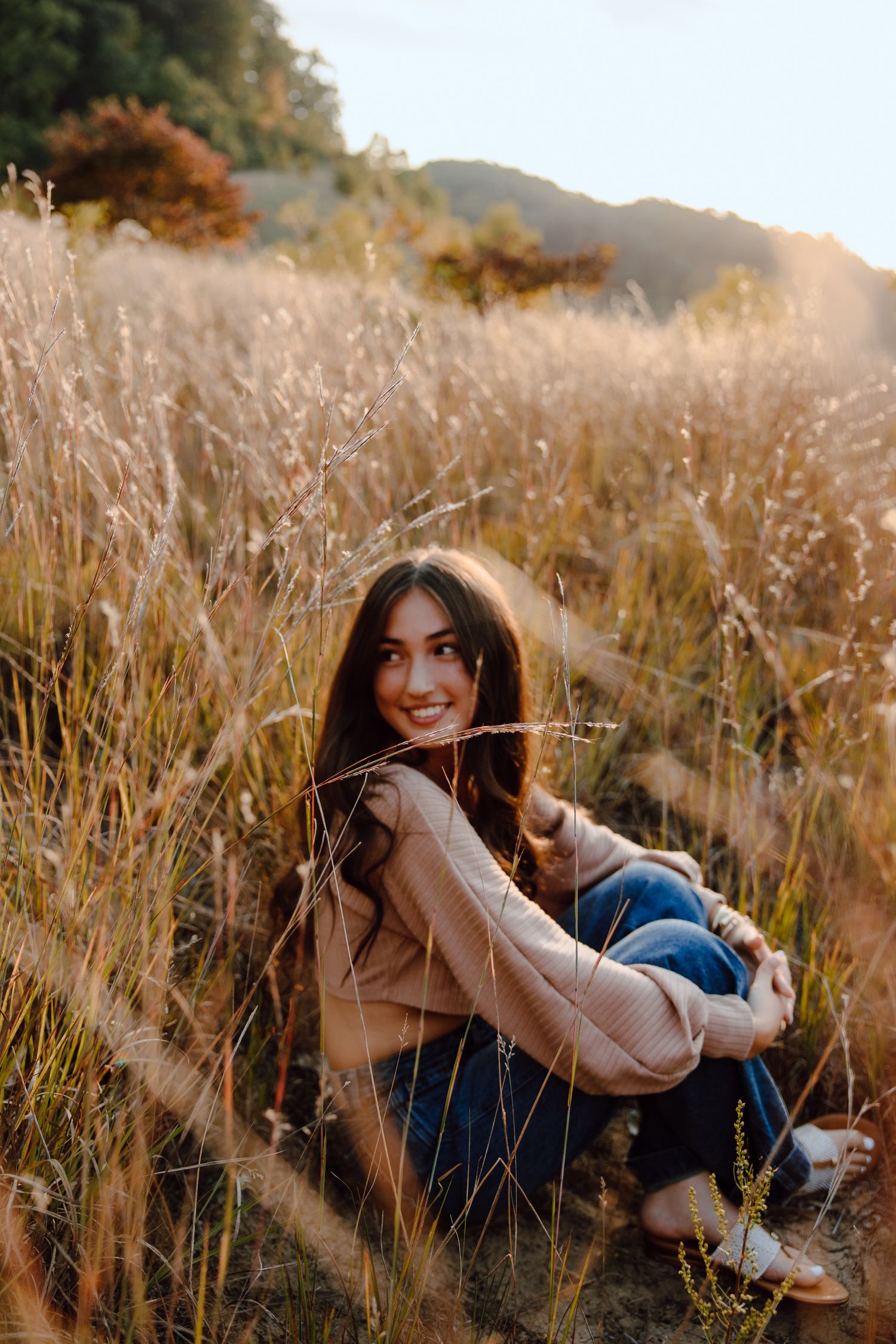 Natural lifestyle portrait in golden field with mountains and sunset in background.