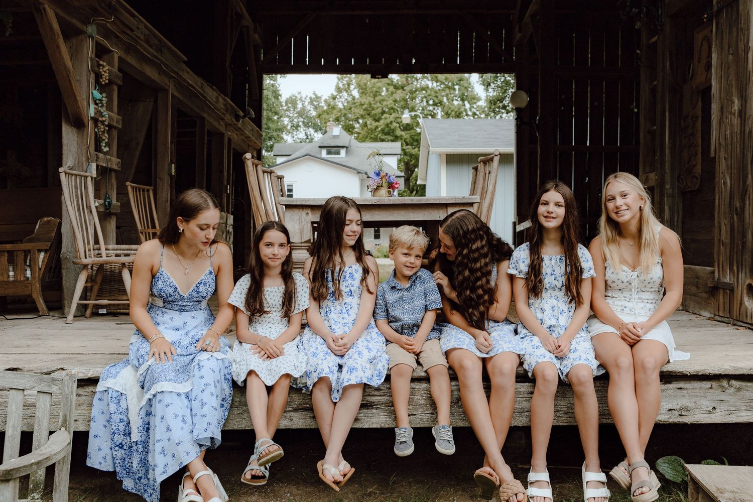 Group photo session on rustic wooden porch with coordinated blue and white outfits.