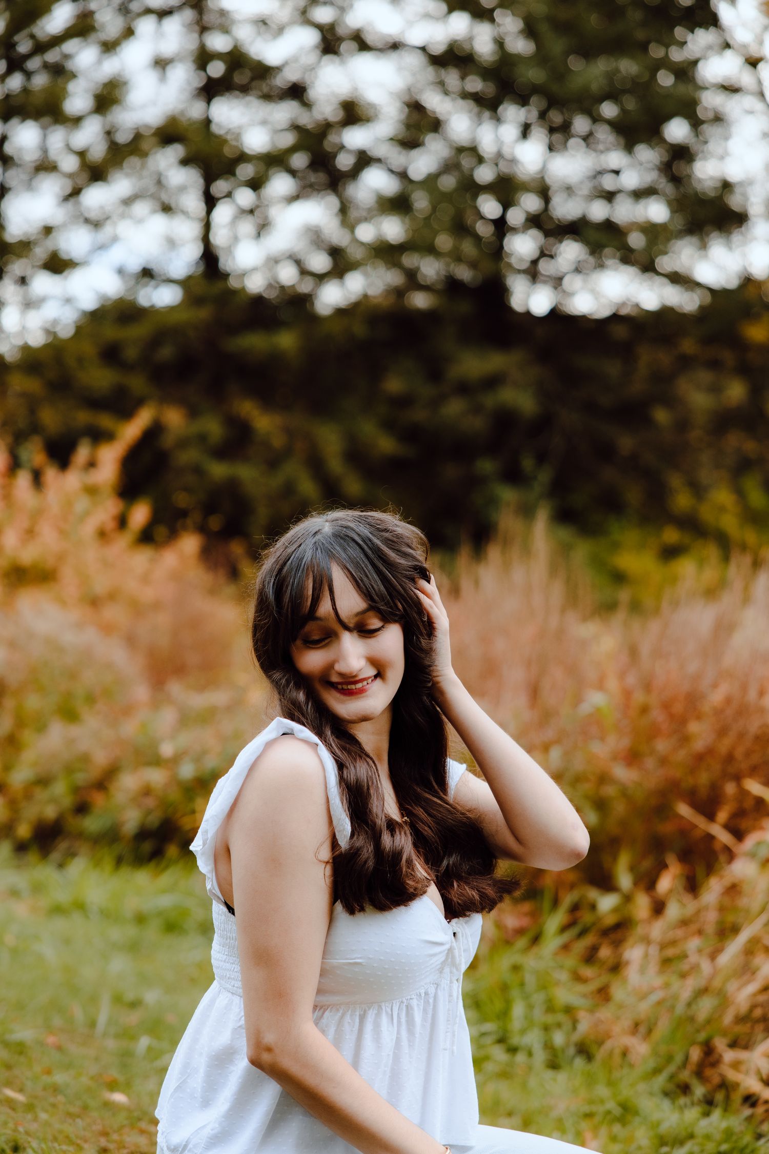 A joyful autumn photoshoot featuring someone in a white top against a warm fall backdrop.
