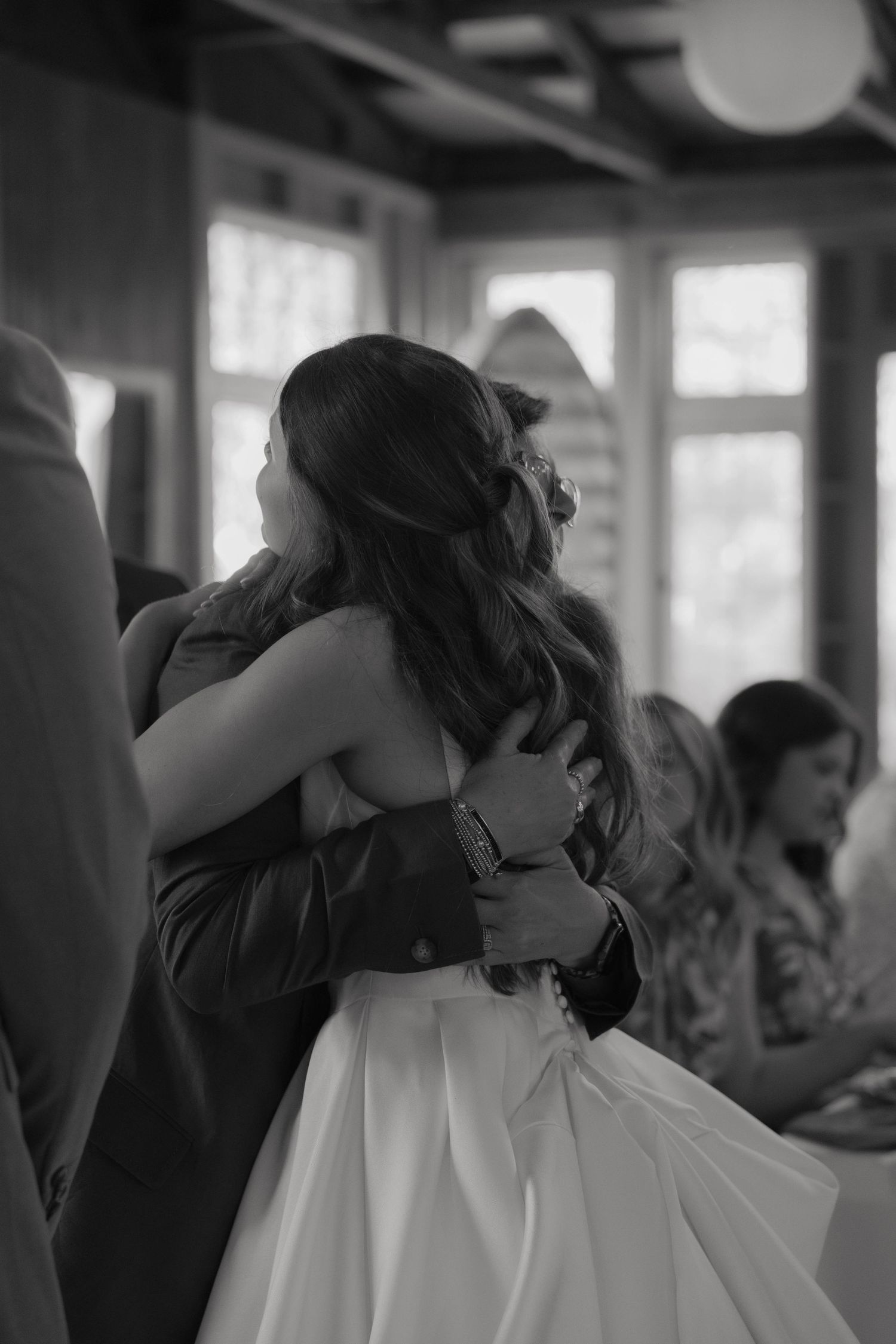 Black and white photo of bride and groom sharing a heartfelt embrace during their wedding reception indoors.