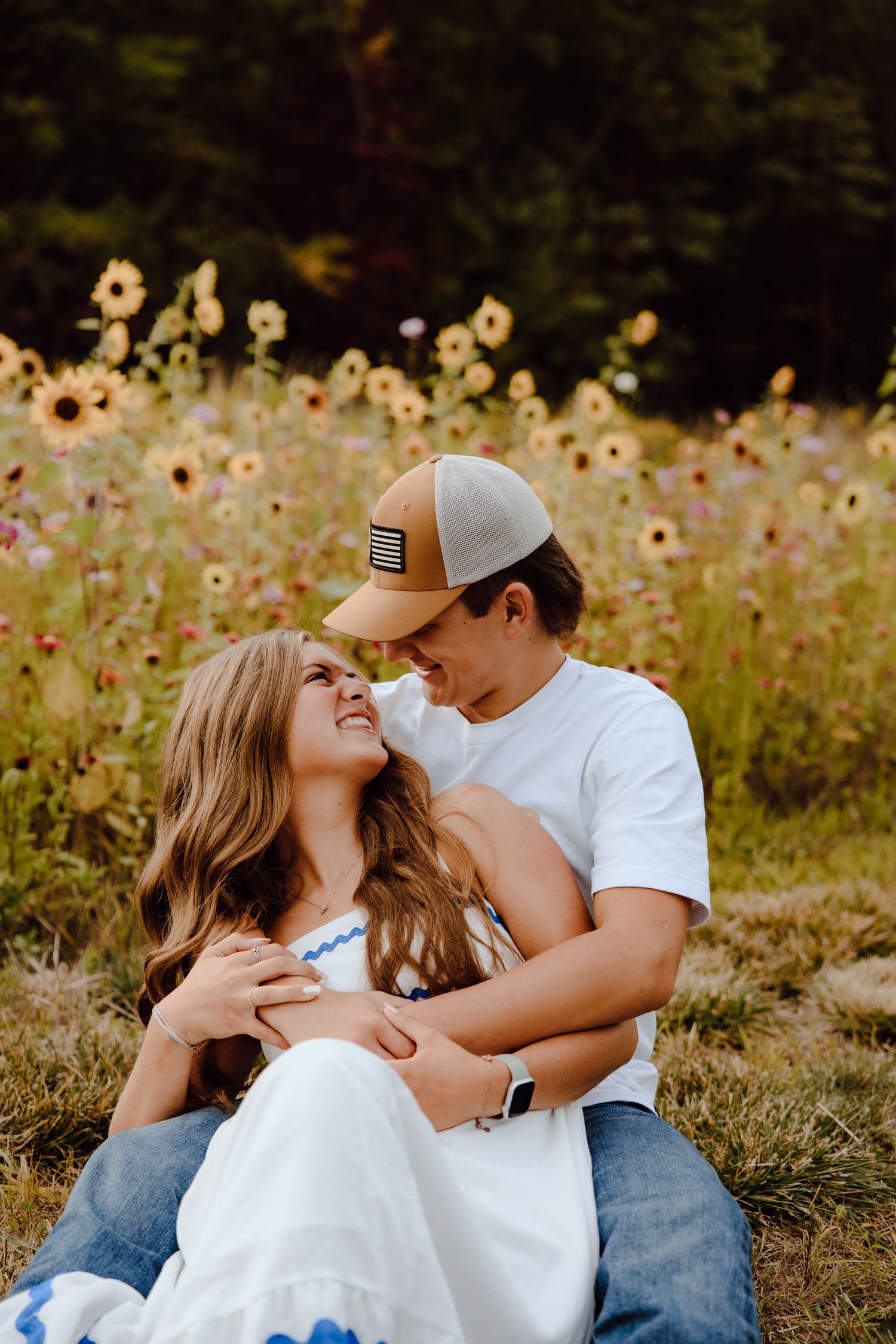 Two people share an intimate moment while sitting in a field of wildflowers.