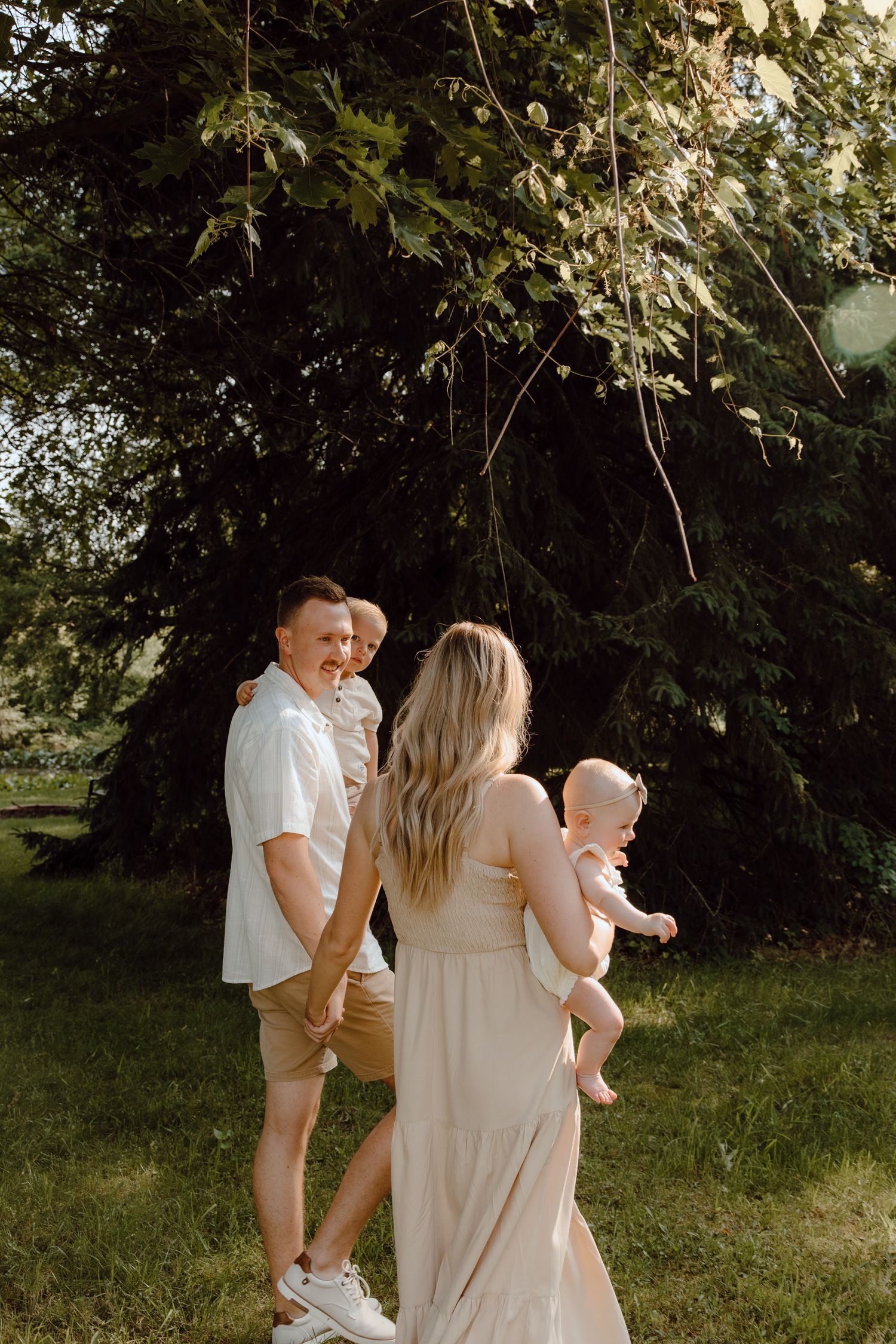 Family enjoying a summer day together under a large tree in a garden setting.