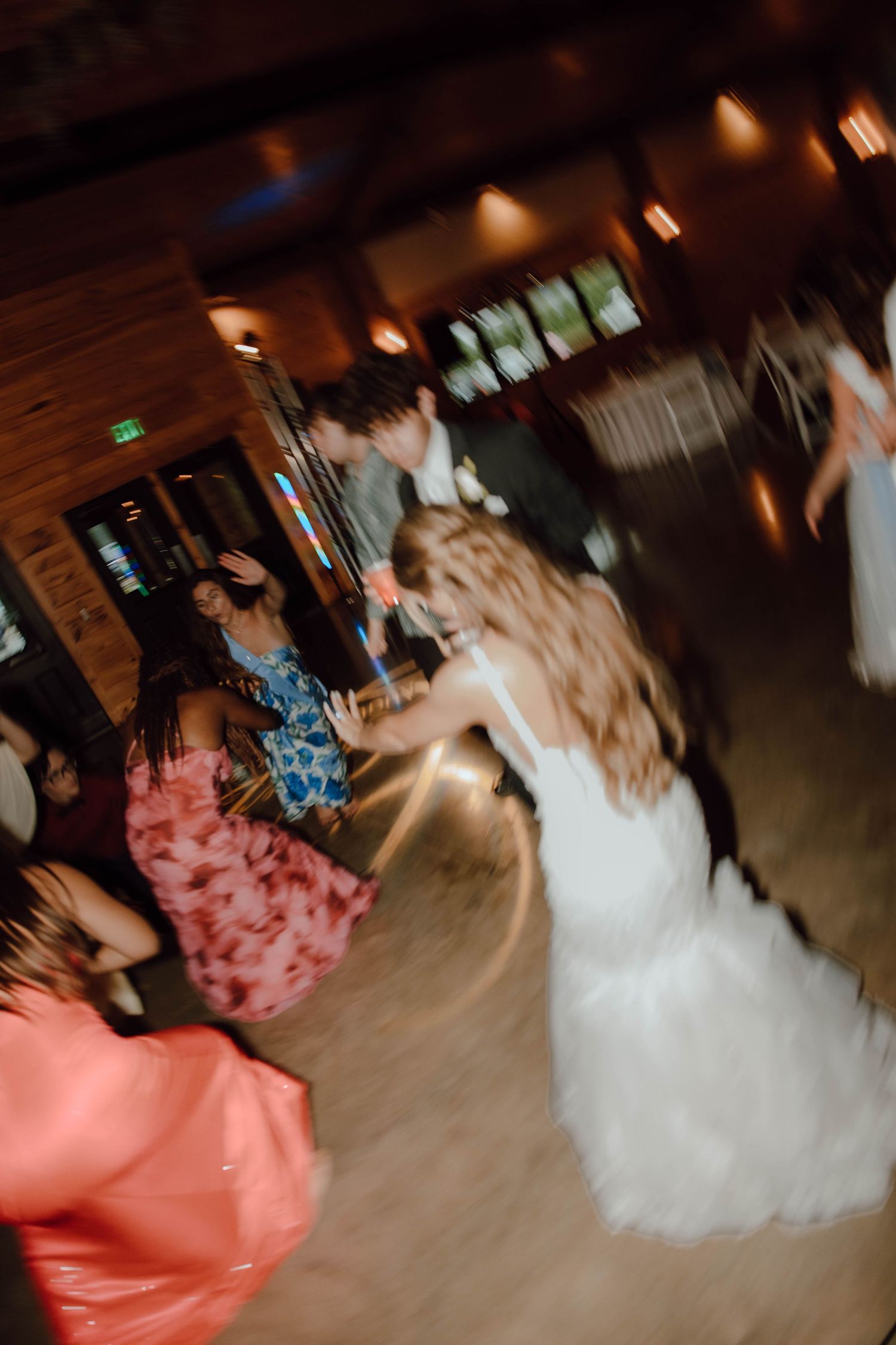 Bride and groom dancing energetically with guests at a rustic wedding reception venue.