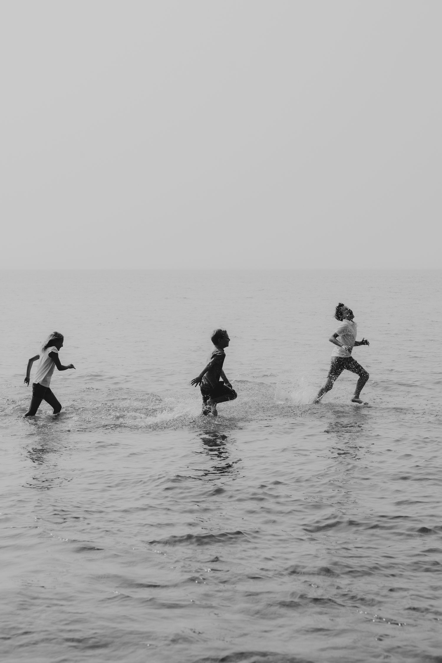 Silhouettes of people jumping and playing in ocean waves.