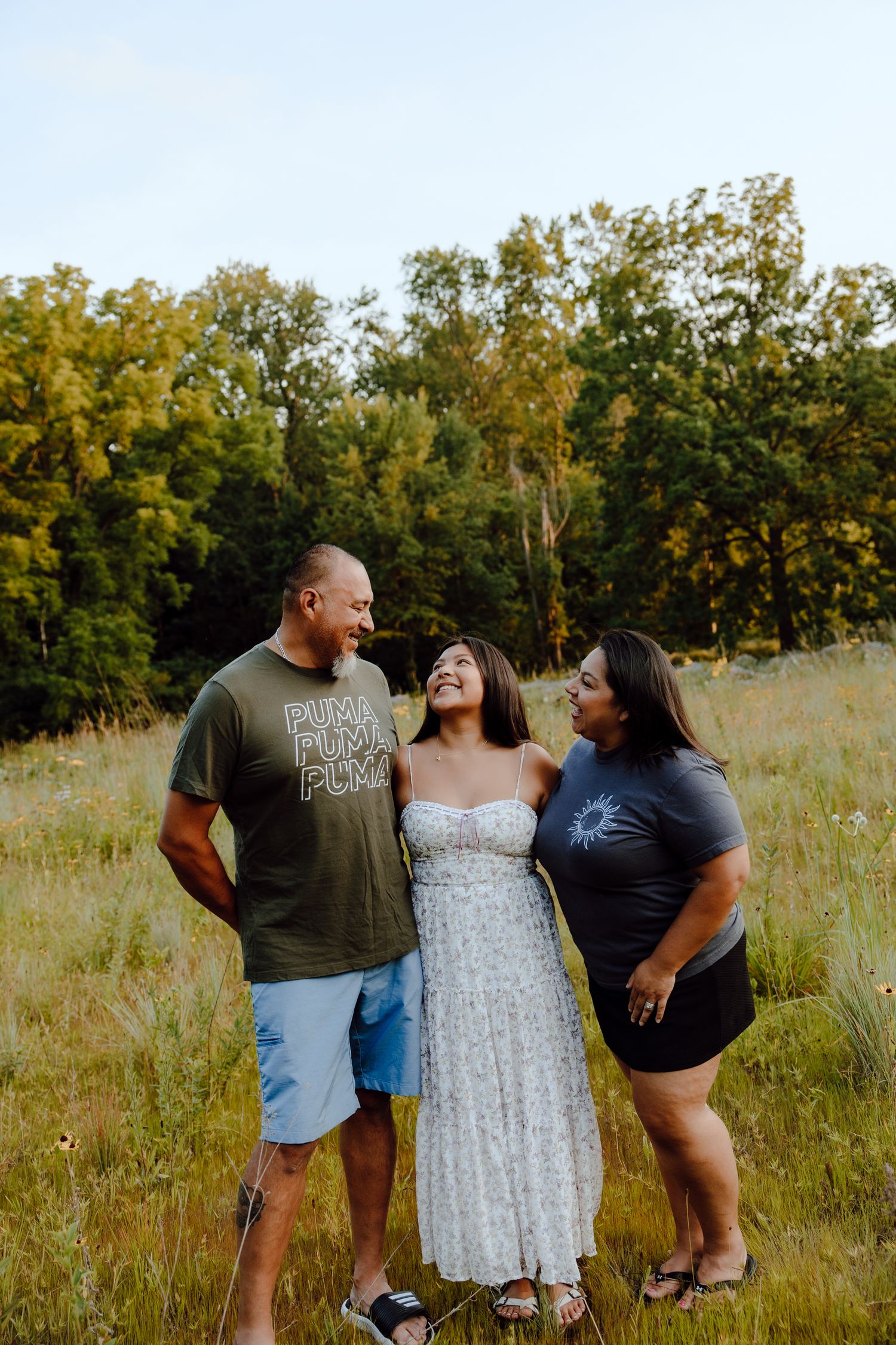 Friends laughing together during a casual outdoor photoshoot in a summer meadow.