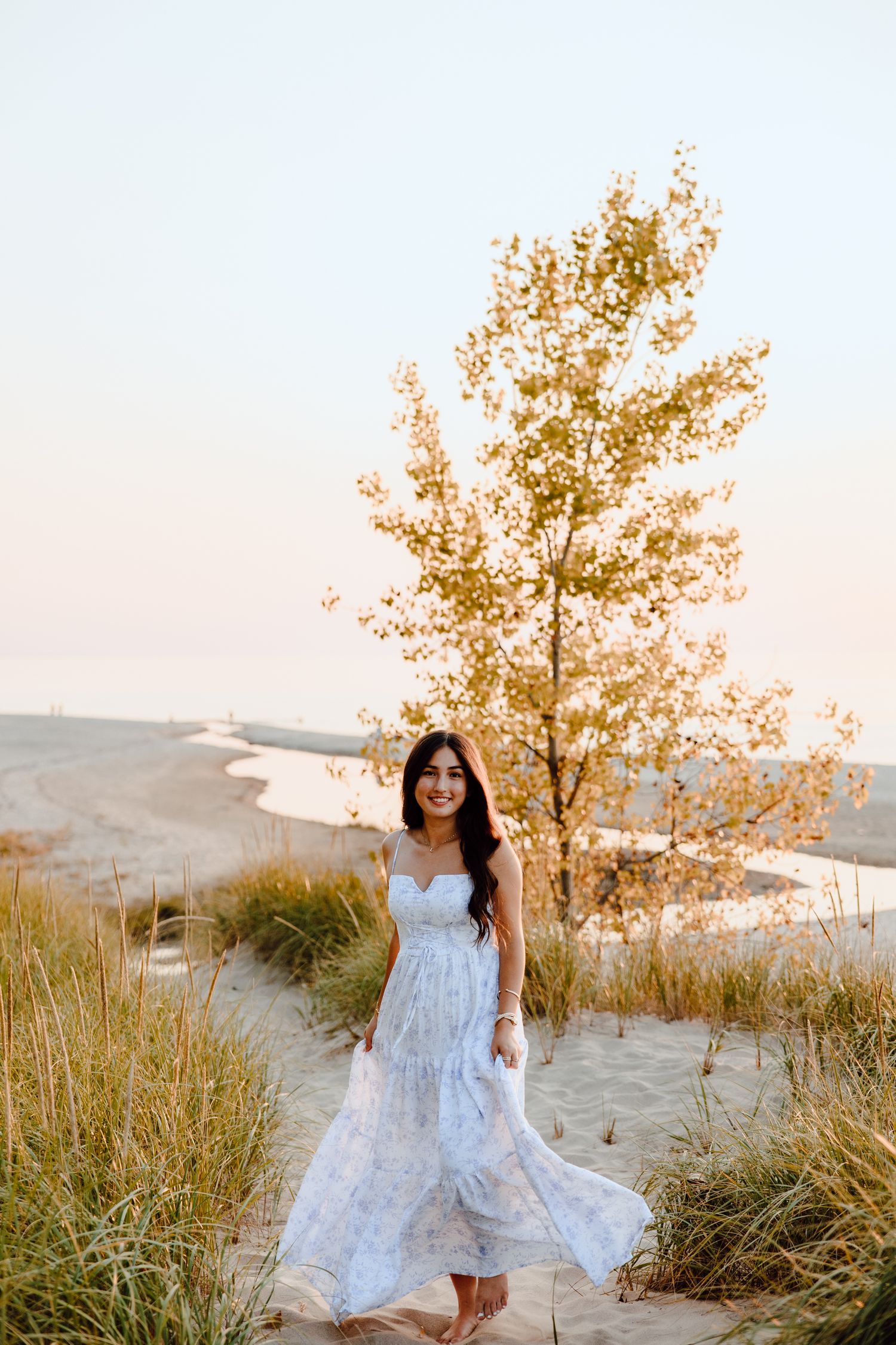 White dress photoshoot among beach grass and trees at golden hour.