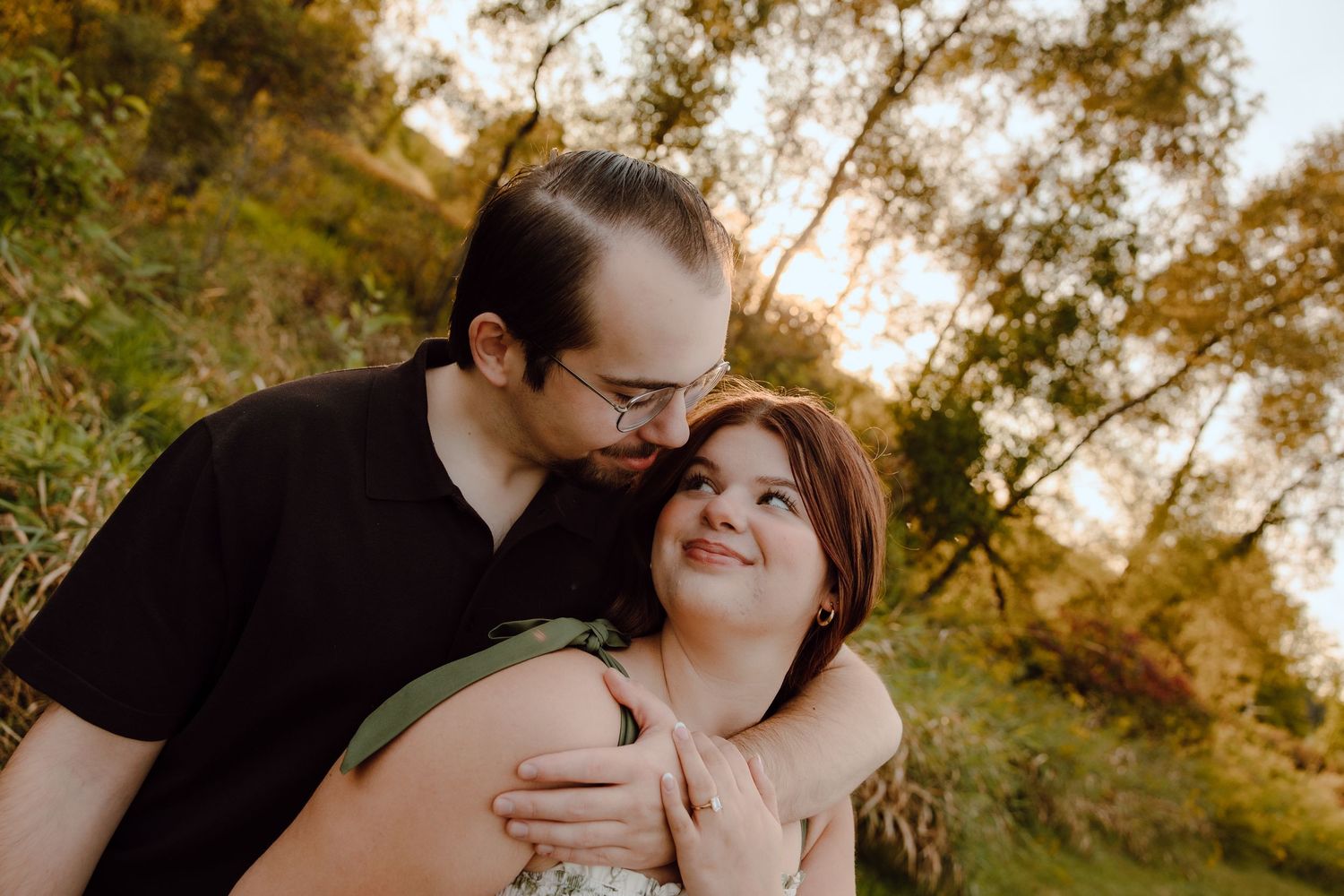 Romantic couple embraces in a sunlit autumn forest setting during an intimate photoshoot.