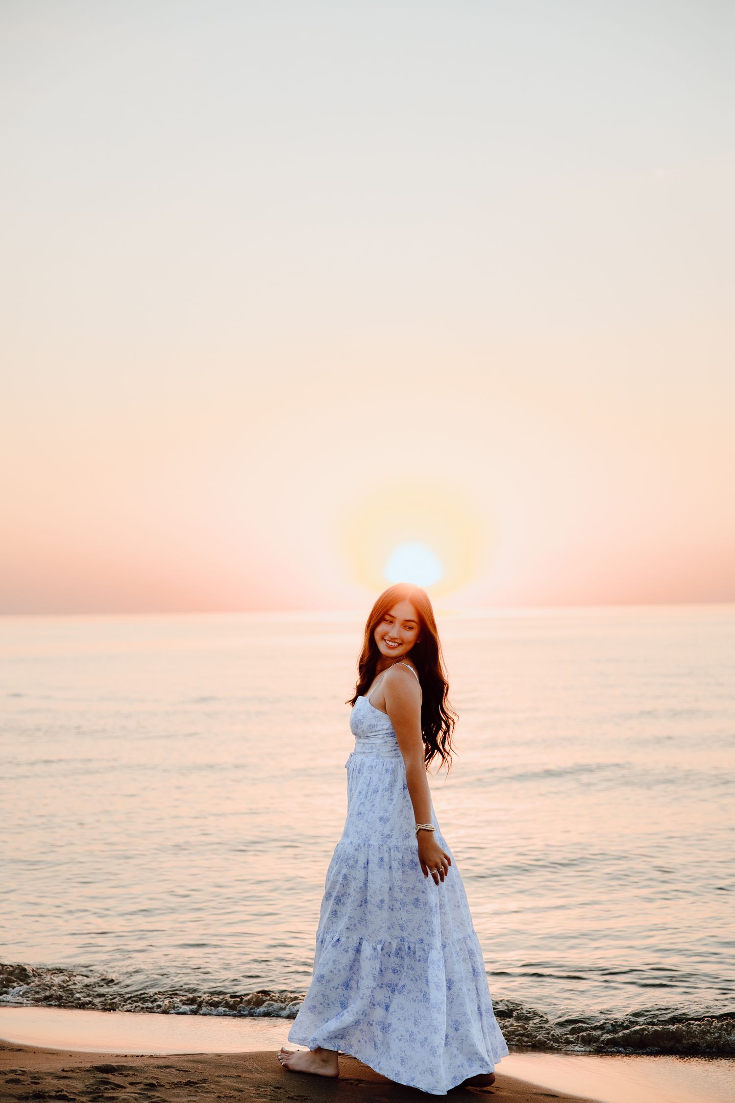 A flowing white dress twirls against a pink sunset beach backdrop.