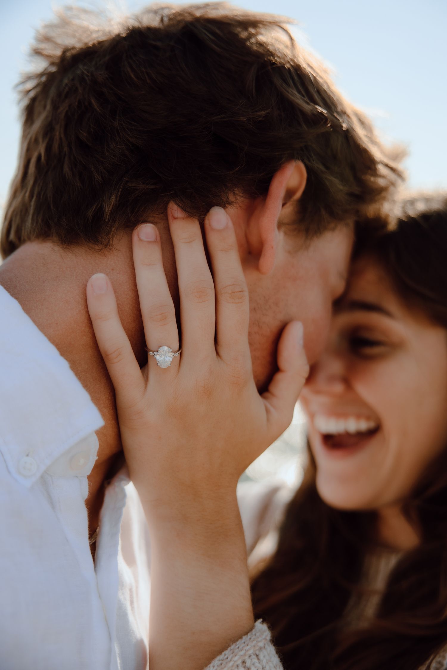 Close-up of engagement ring and joyful laughter during romantic moment.