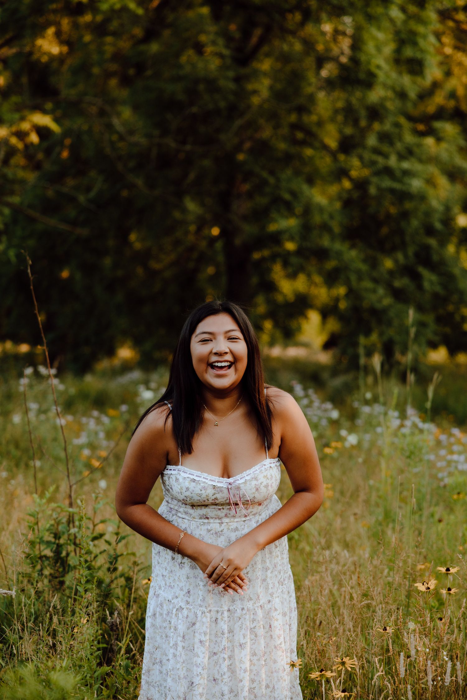 Candid laughter during a summer photoshoot in a field of white and yellow flowers.