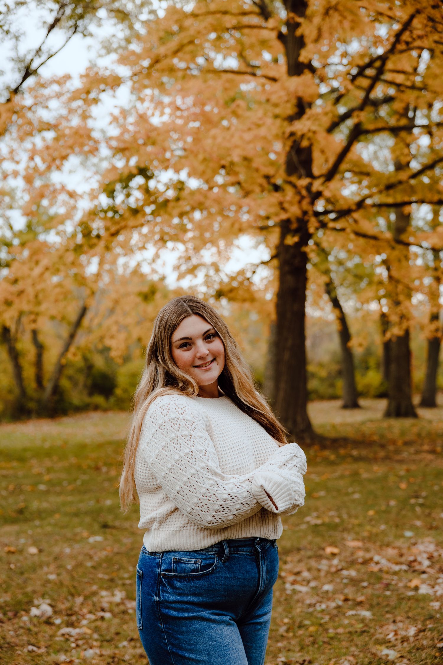 Casual autumn portrait session with cream sweater and jeans among fall foliage.