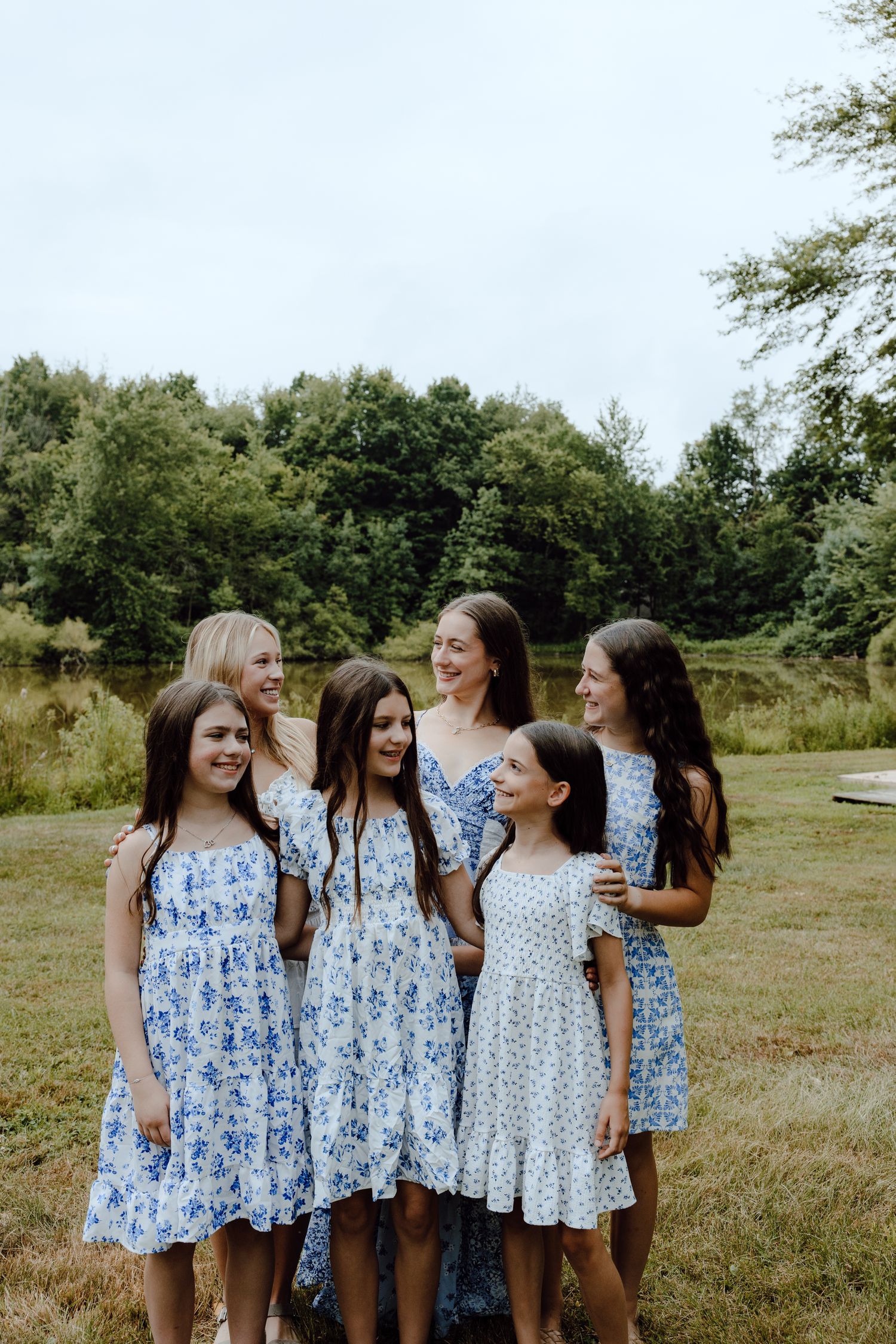 A cheerful group wearing matching blue and white floral dresses gathers outdoors.