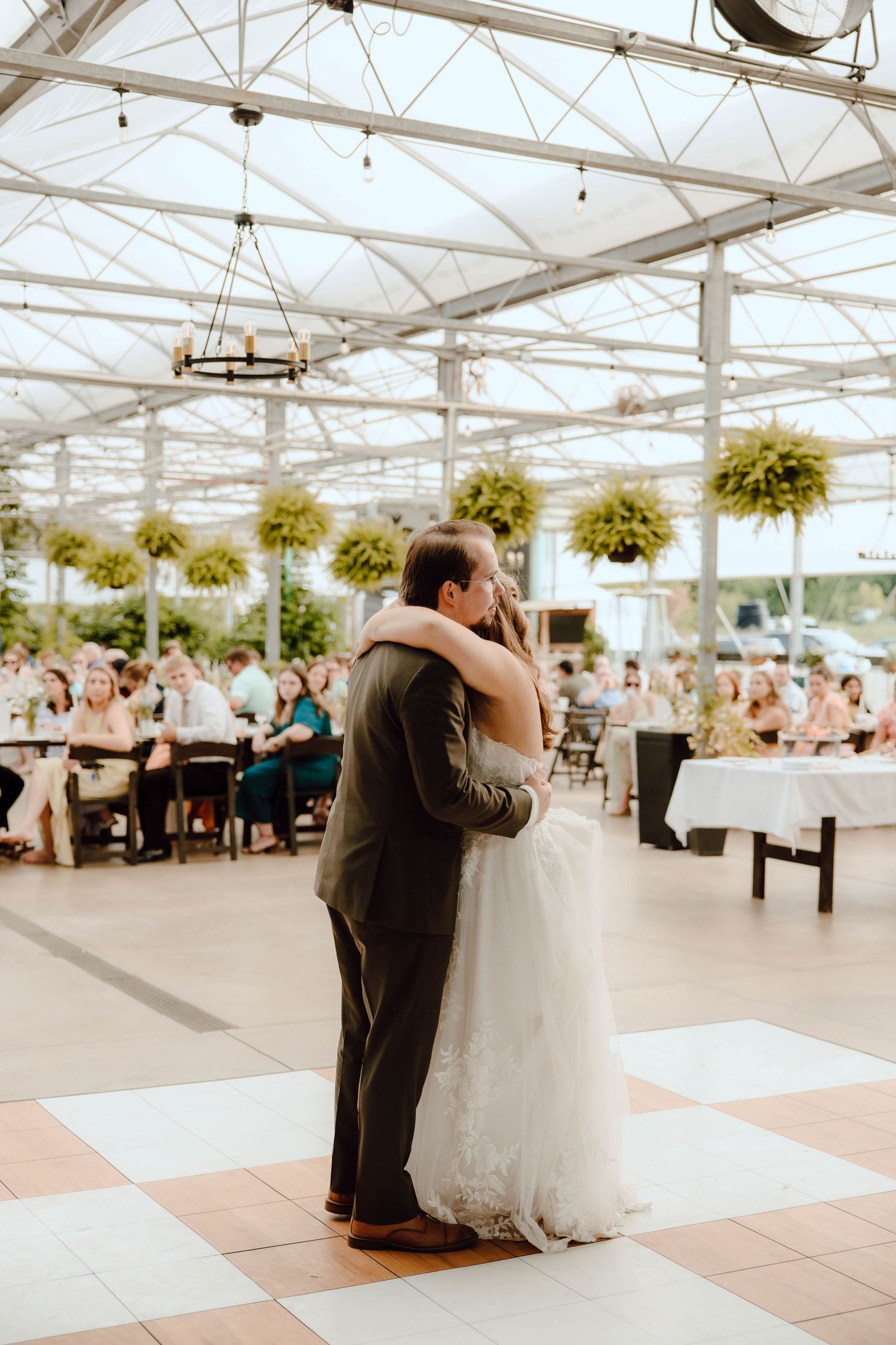 Bride and groom sharing first dance in elegant glass greenhouse wedding reception venue.