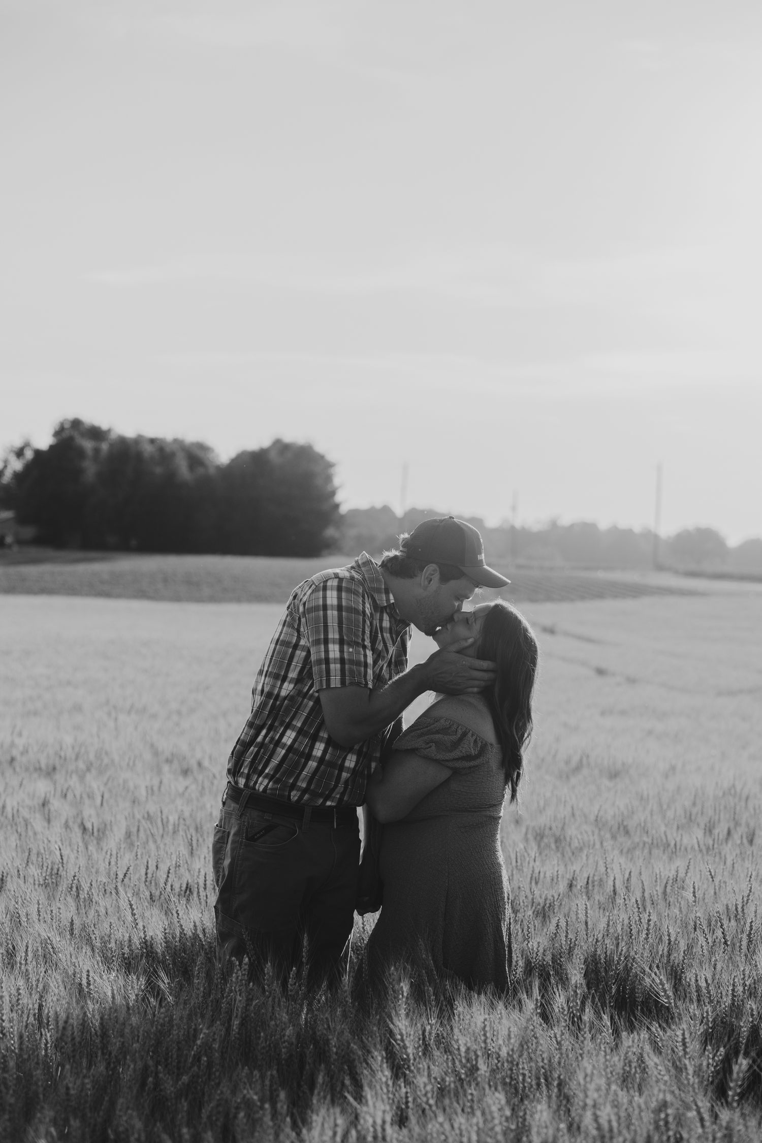 A couple embraces in a misty wheat field during a moody black and white photoshoot.
