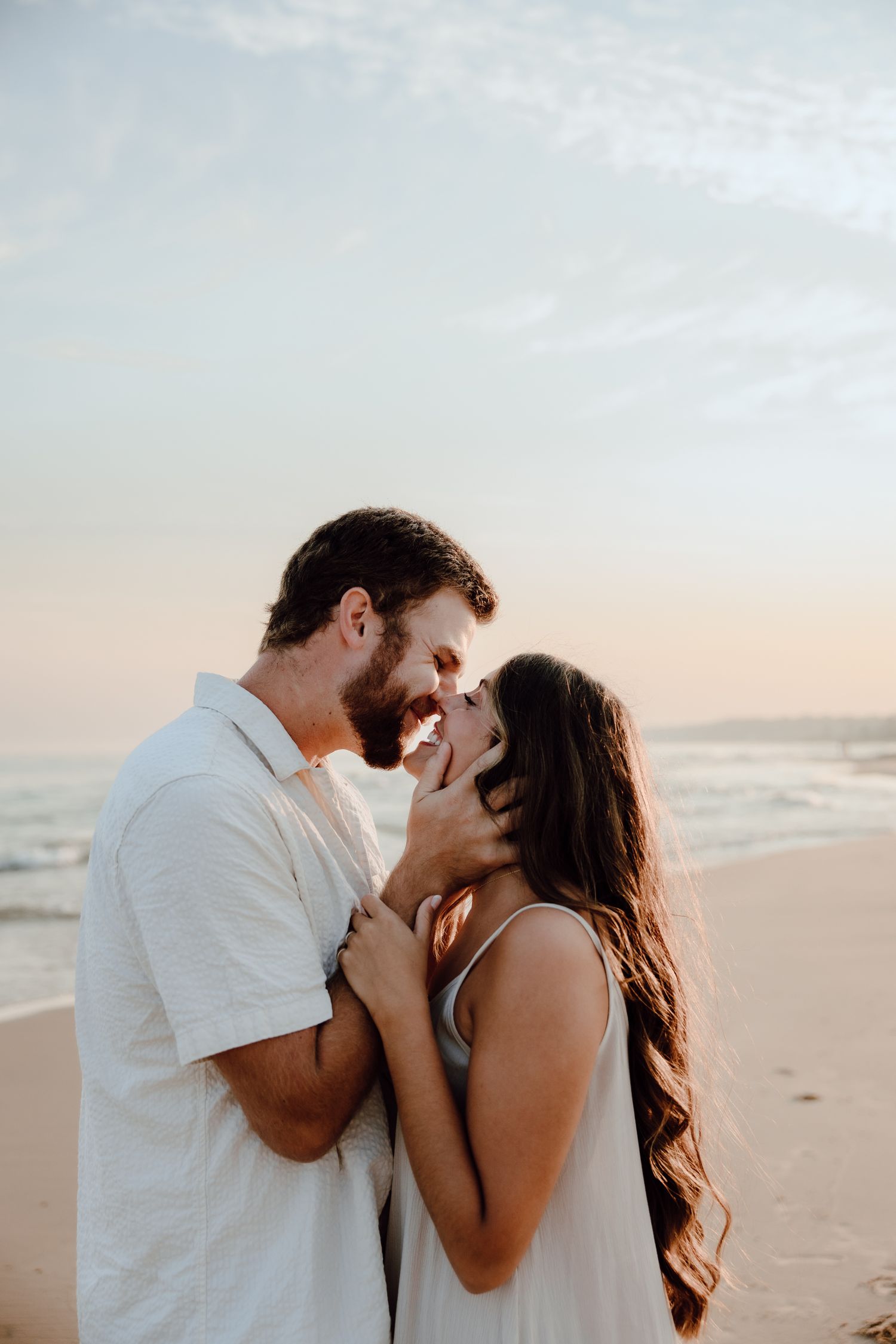 A romantic couple shares an intimate moment on the beach at sunset.