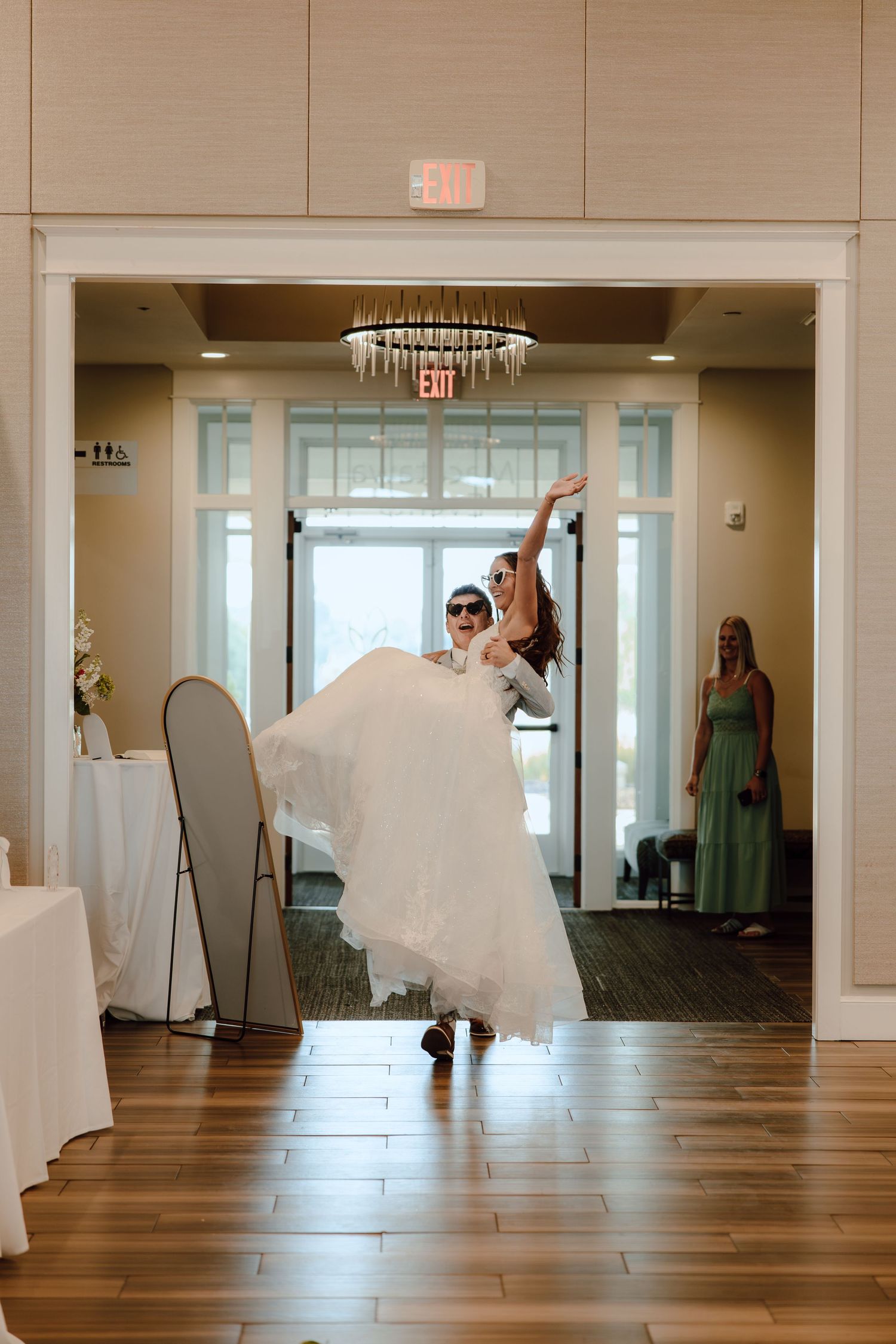 Bride in white ball gown being lifted by groom as they make a grand entrance into their wedding reception.