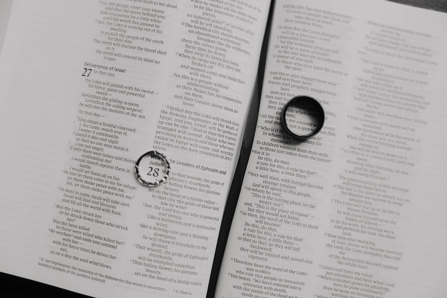Black and white photo of wedding rings resting on an open Bible, symbolizing faith and marriage commitment.