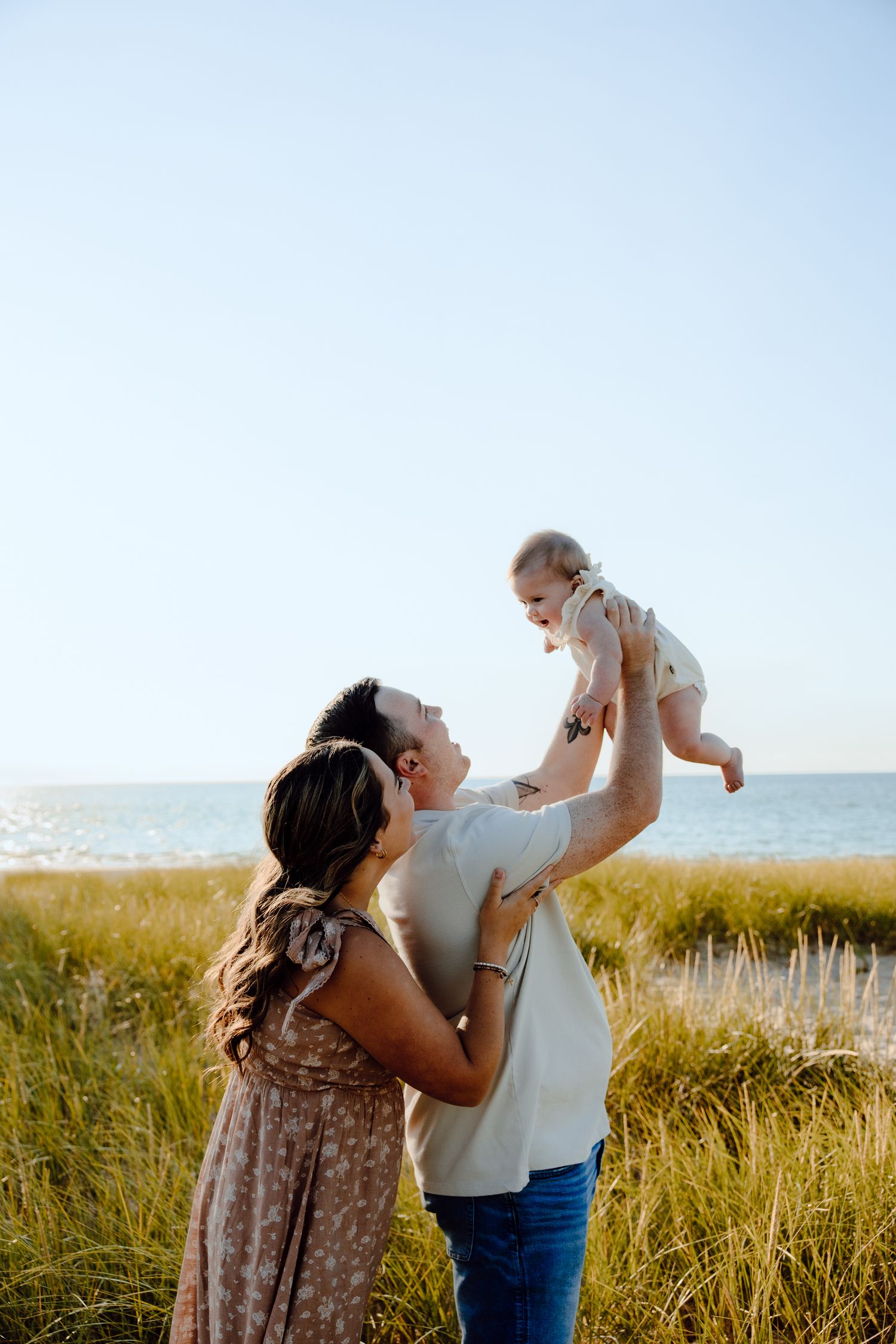 Joyful family moments captured in golden light on a beach with tall grass.