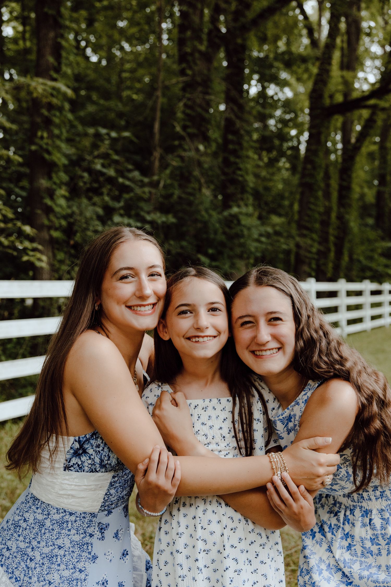Friends in matching blue and white dresses laughing and embracing outdoors.