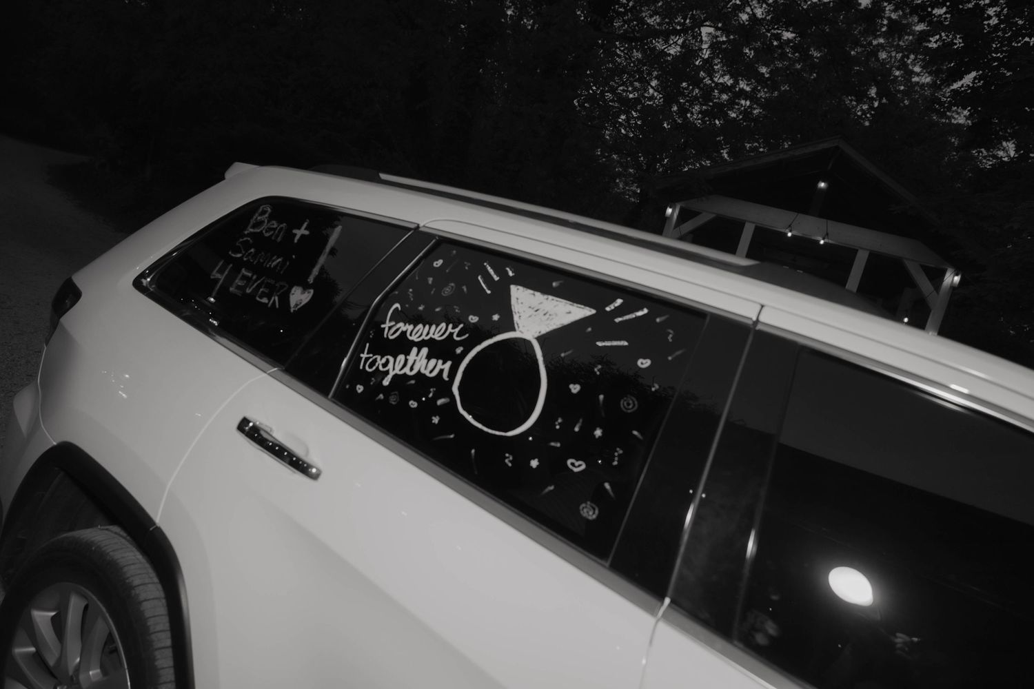 Black and white photo of a white SUV rear window with 