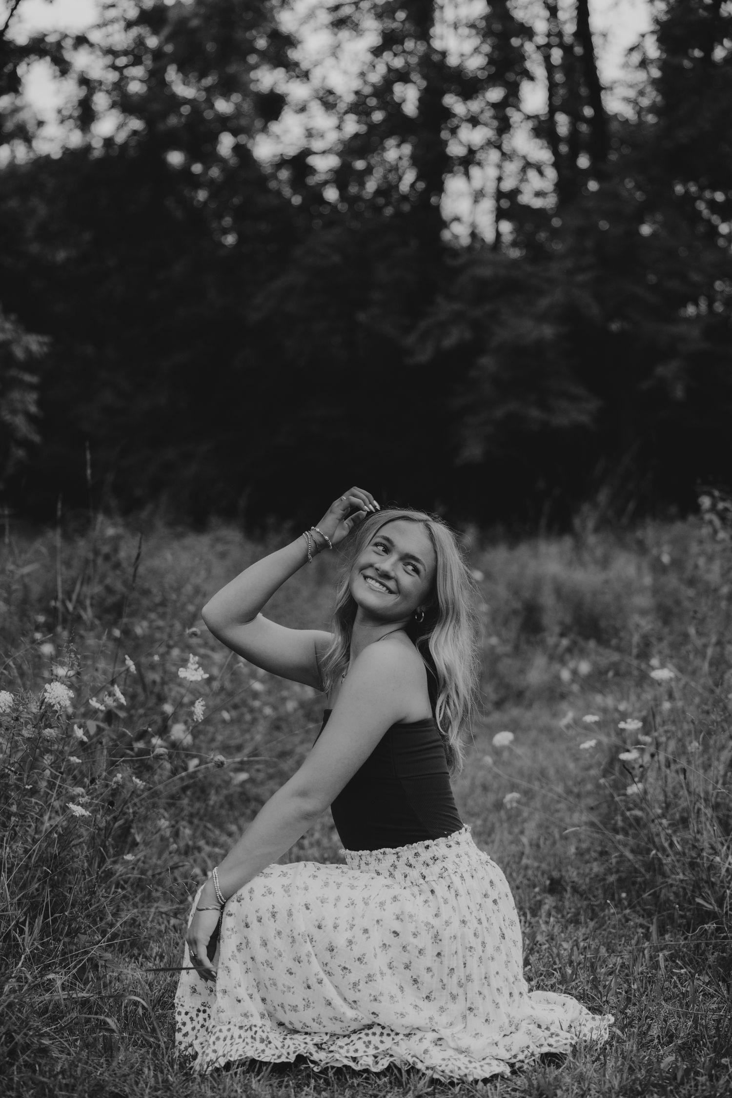 Black and white photo of someone in a flowing dress moving freely in a meadow.