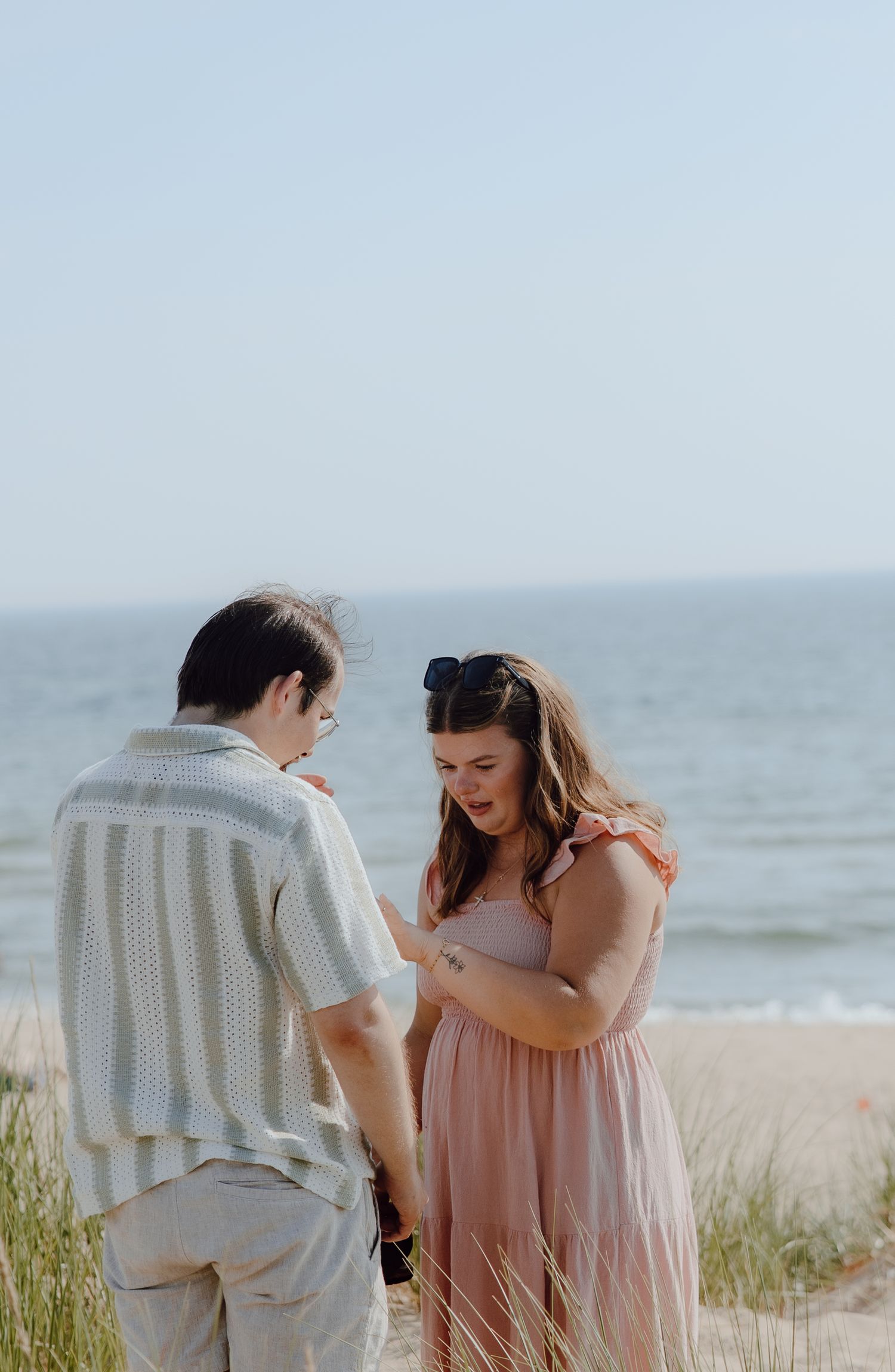 A heartfelt moment shared between two people on a beach with sea grass.