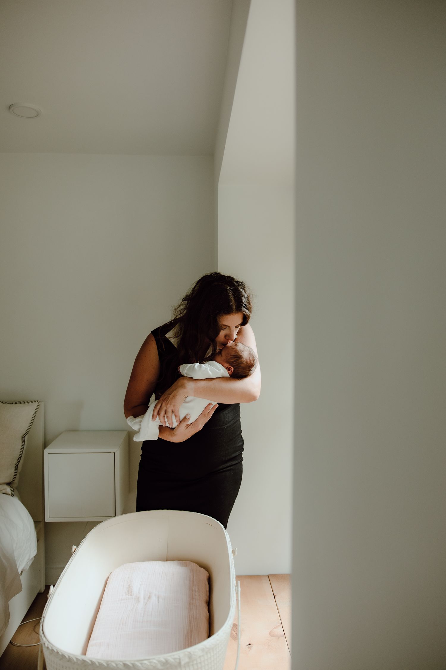 Tender moment in a bright nursery room with white bassinet.