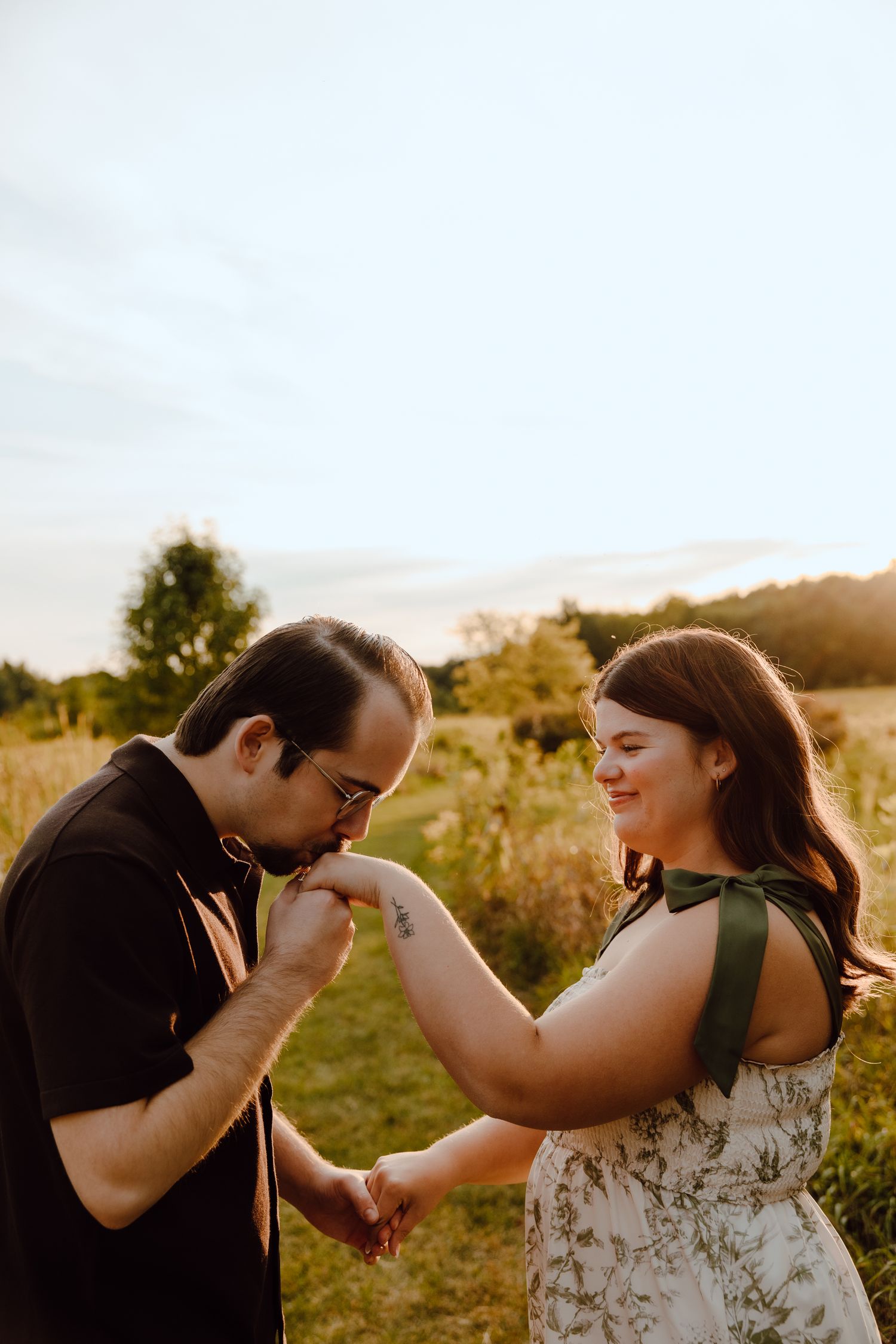 A couple shares a playful moment in golden sunlight during an engagement photoshoot.