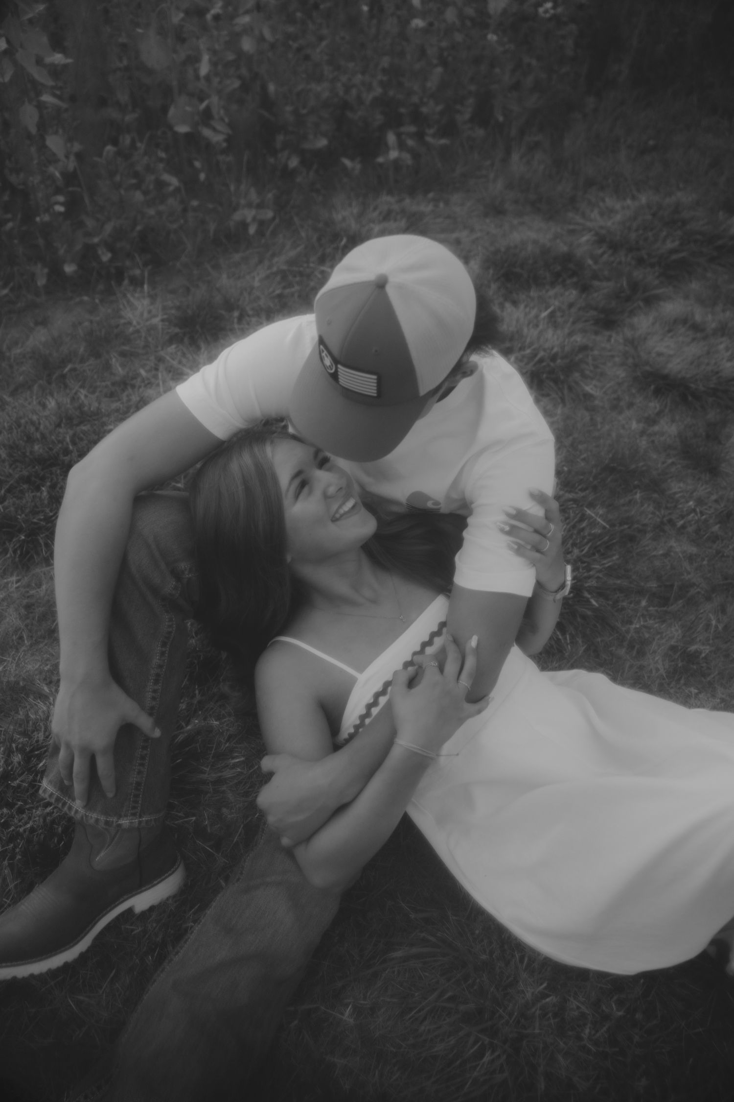Two people lay together in the grass during an intimate black and white photoshoot.