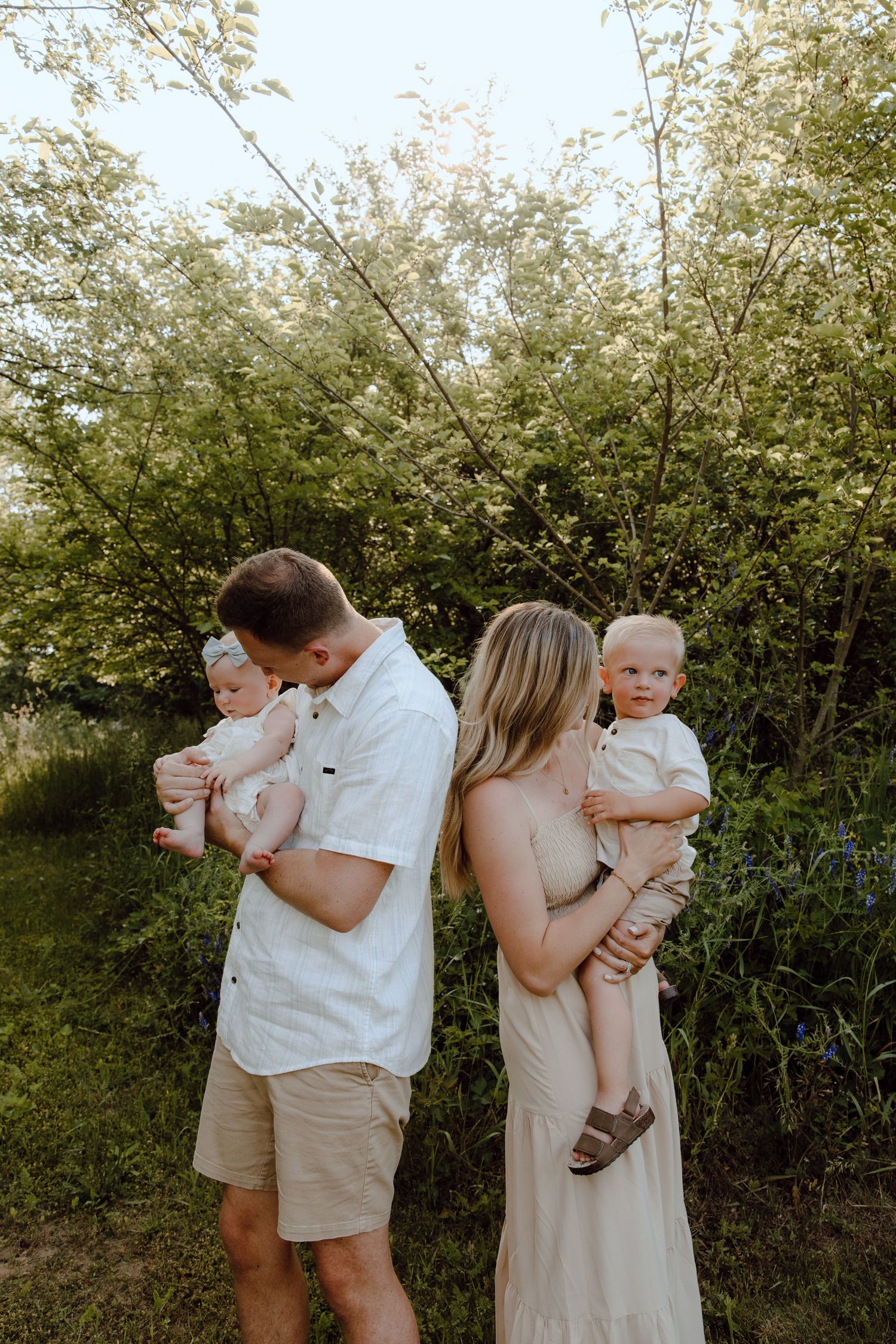 Candid family moment captured outdoors with natural greenery backdrop.
