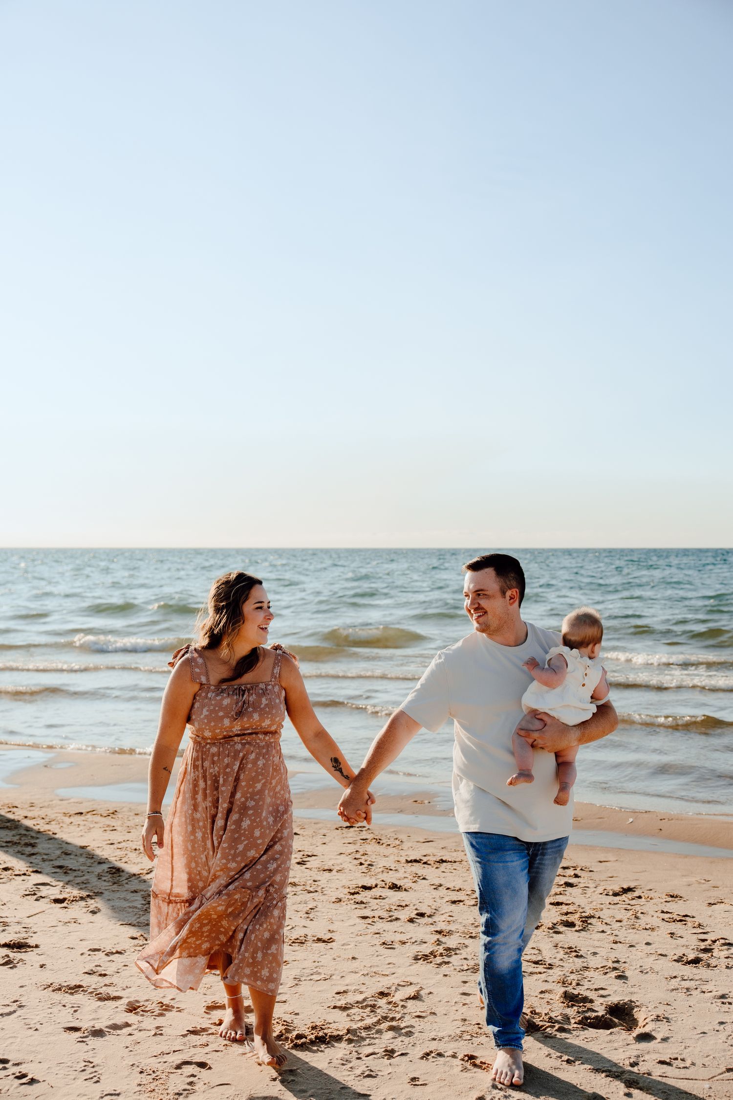 Family walking and playing together along a sandy beach shoreline.