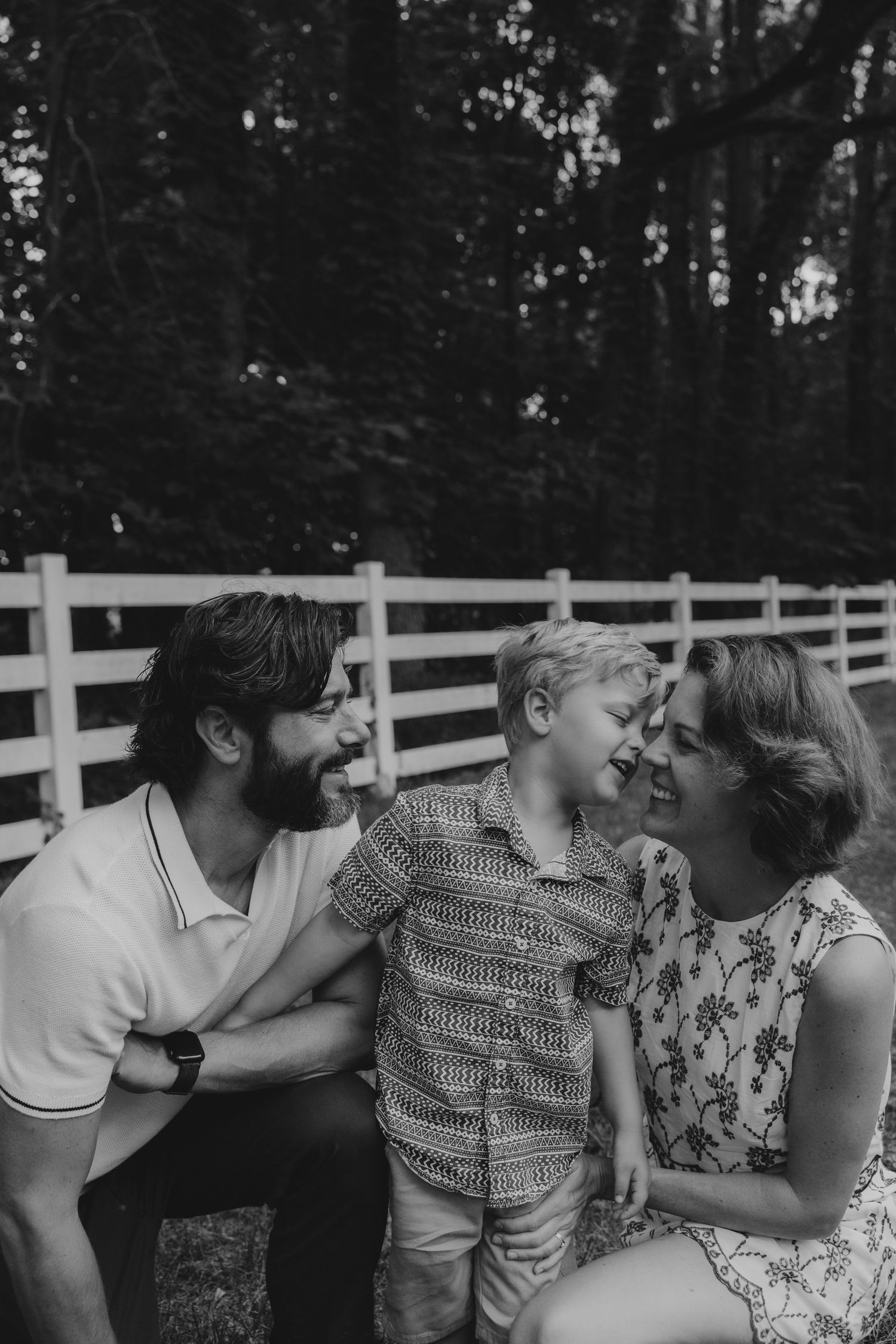 Black and white portrait of family members sharing kisses and embraces outdoors.