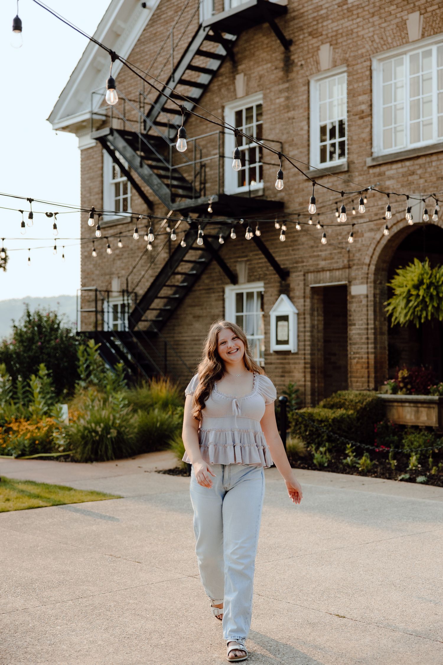 Casual portrait series outside a historic brick building with string lights and architectural details.