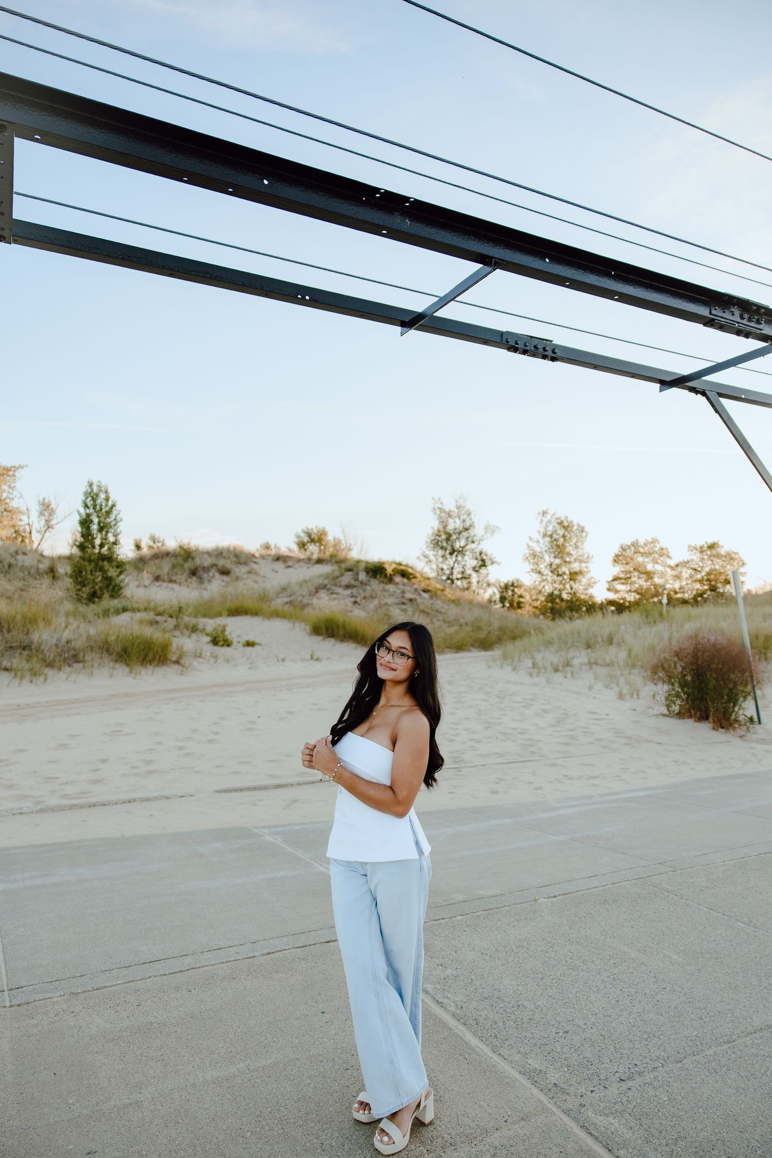 White flowing dress contrasts against desert landscape with power lines overhead.