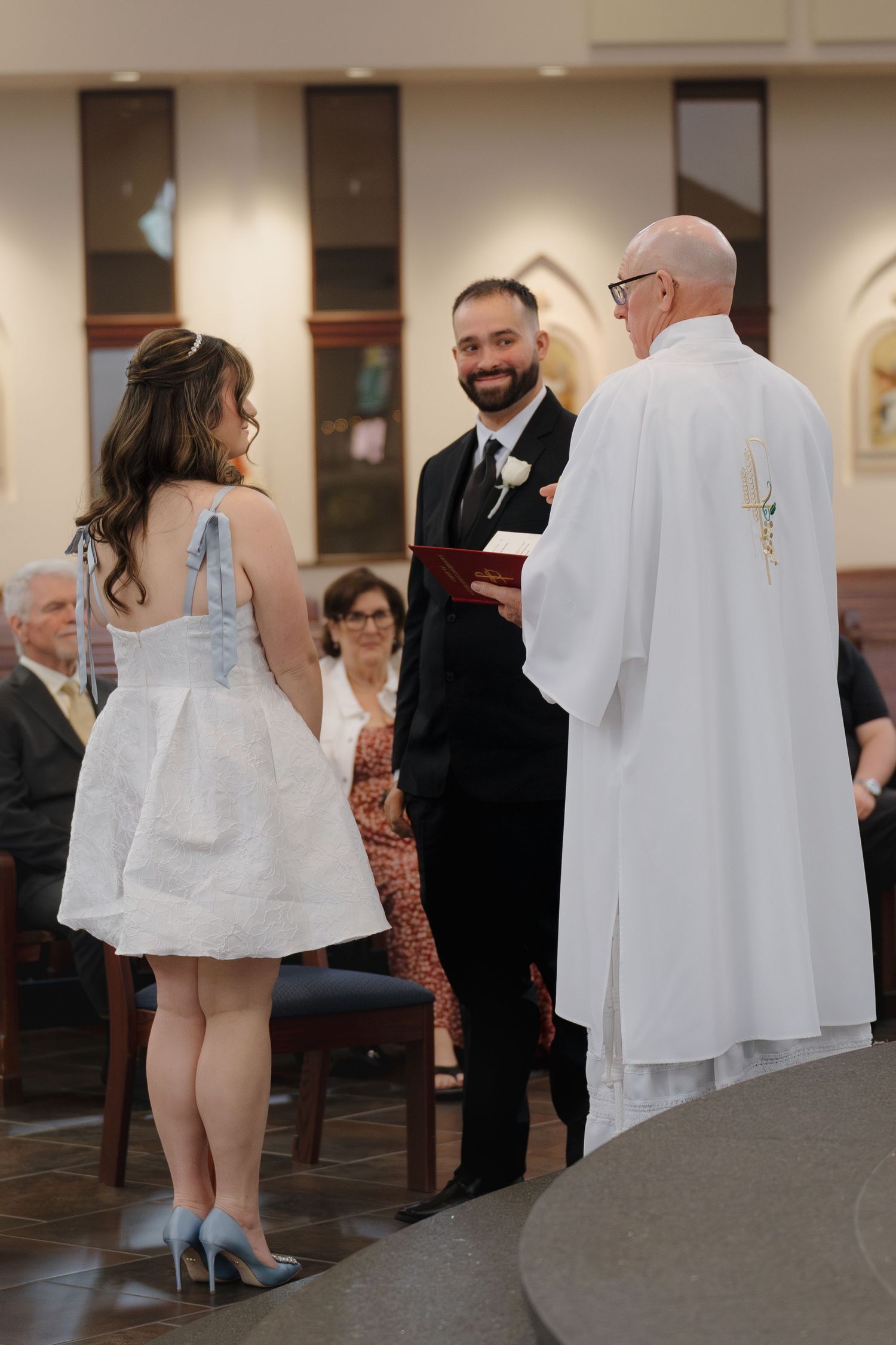 Bride and groom exchange vows before a priest at the altar during an elegant church wedding ceremony.