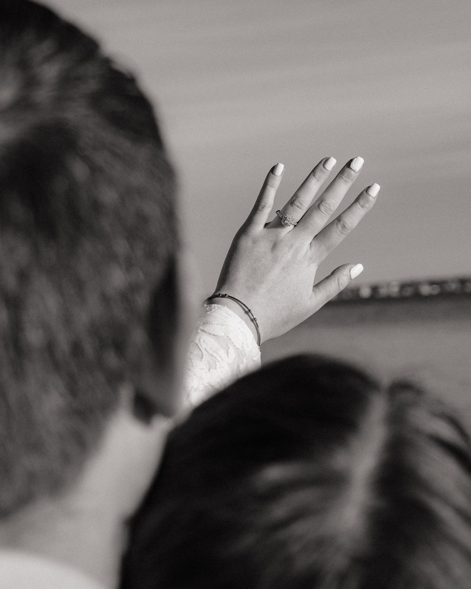Black and white photo of two people, one raising a hand with a ring and bracelet, symbolizing a romantic moment.