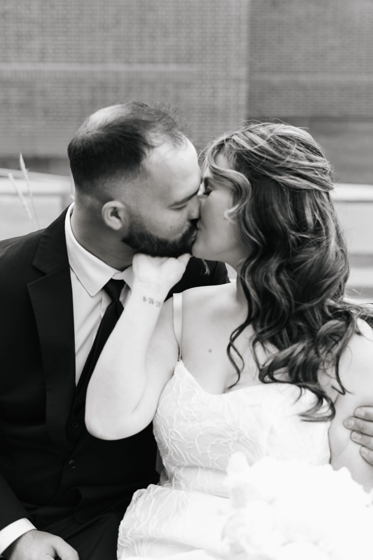 Black and white photo of a bride and groom sharing a romantic kiss on their wedding day.