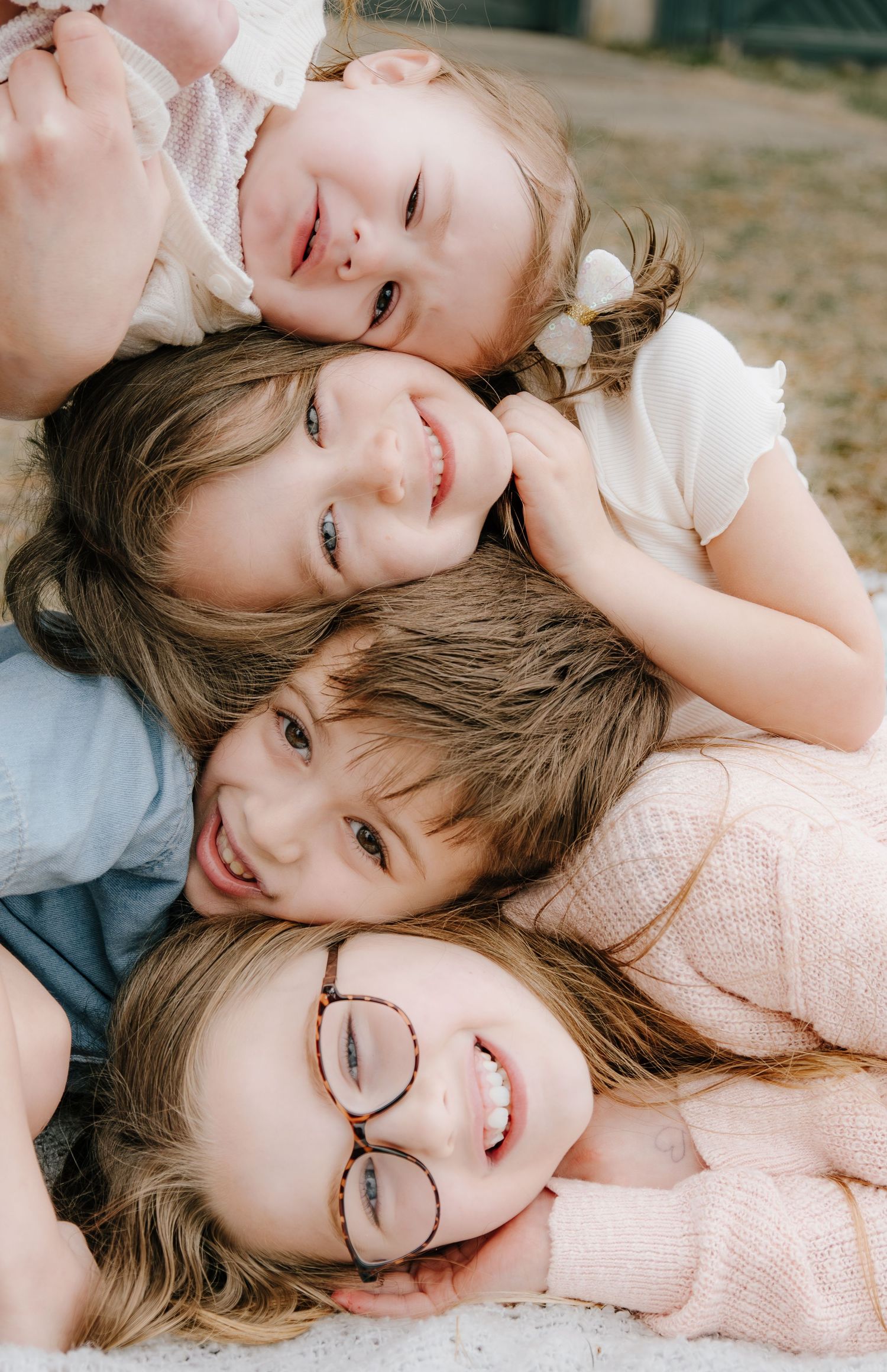 Four young girls smiling and stacking their heads together in a sweet and playful portrait photo.
