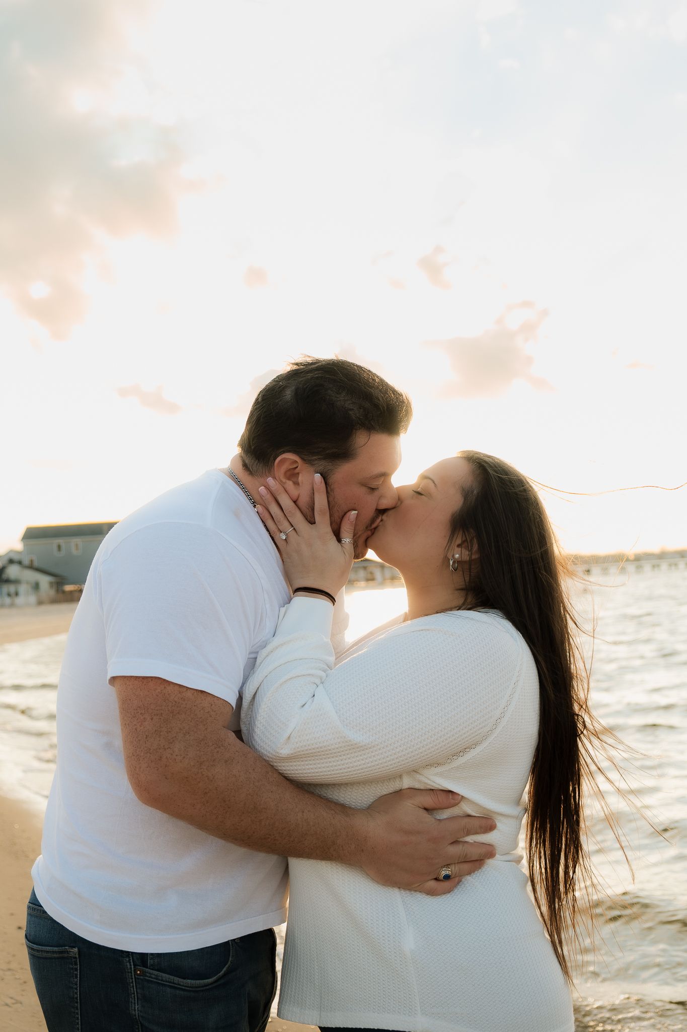 Couple sharing a romantic kiss on the beach at golden hour.