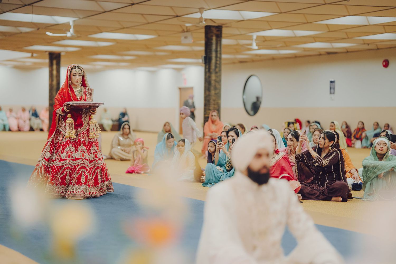 Panoramic shot of a wedding ceremony space with colorful traditional outfits and decorative elements.