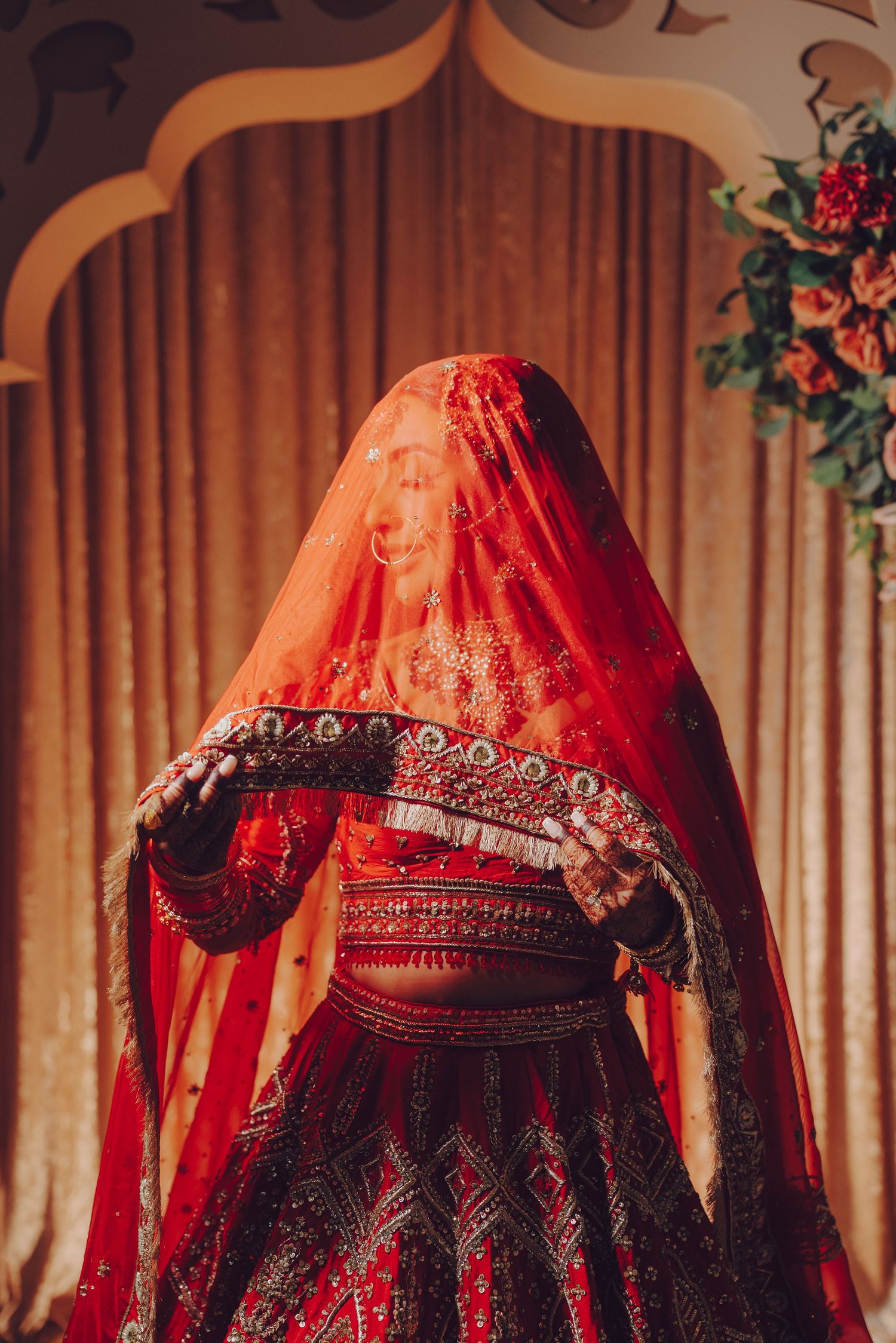 Traditional red and gold Indian bridal lehengas displayed in a row with intricate embroidery details.