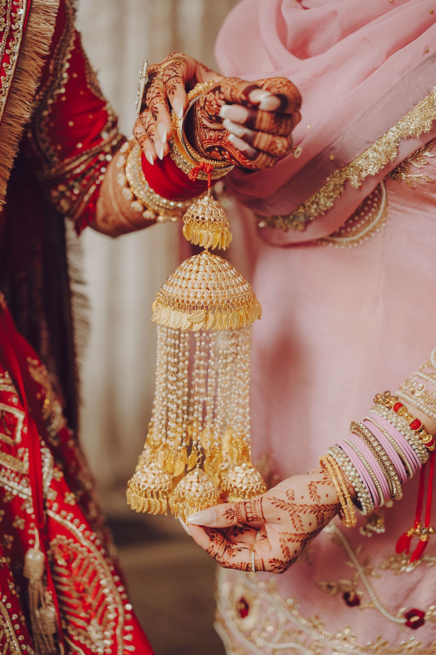 Close-up of traditional kalire and bangles worn by an Indian bride in red and gold.