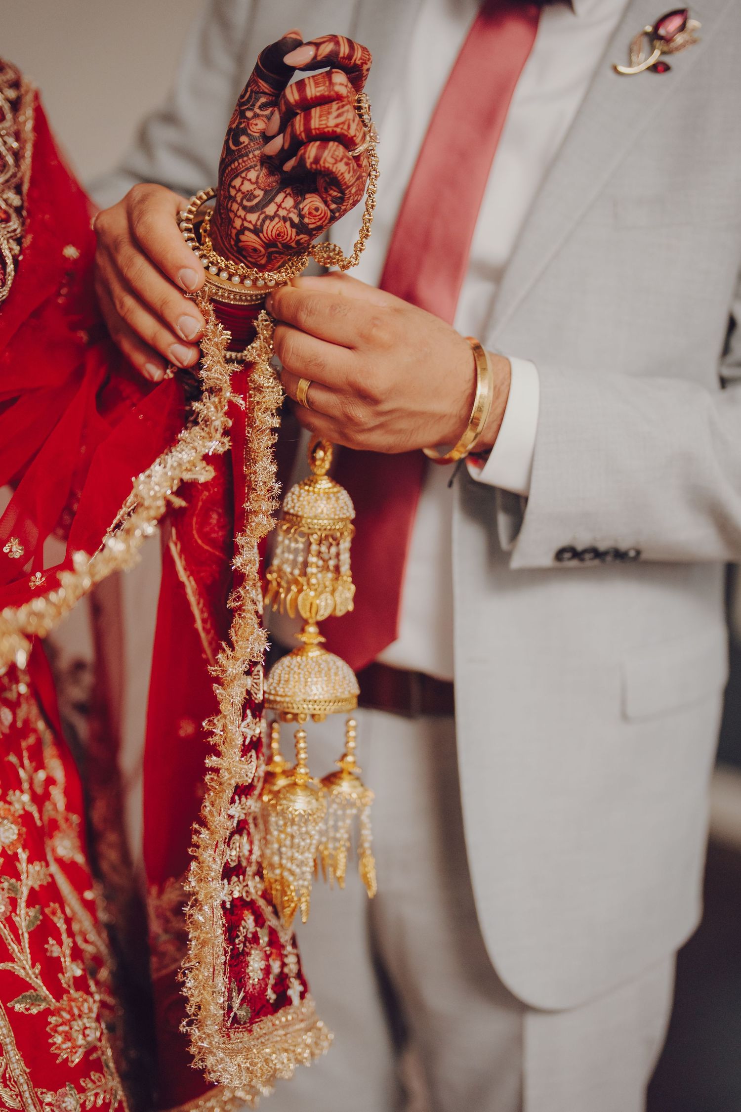 Close-up details of ornate gold and red traditional Indian wedding jewelry and decorations.