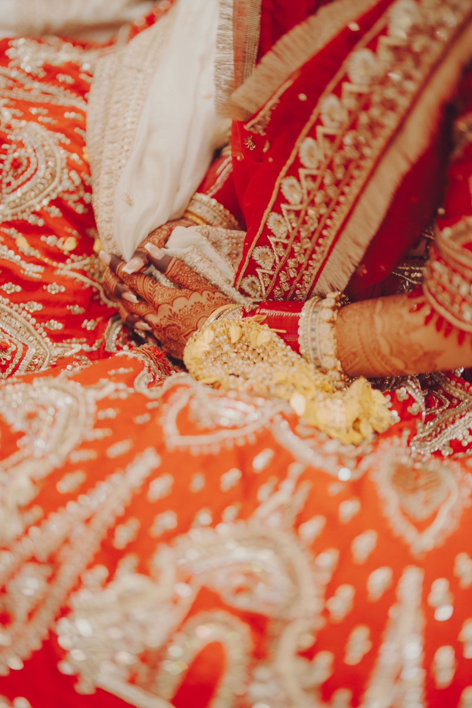 Close-up details of traditional red and gold wedding attire against patterned fabric.